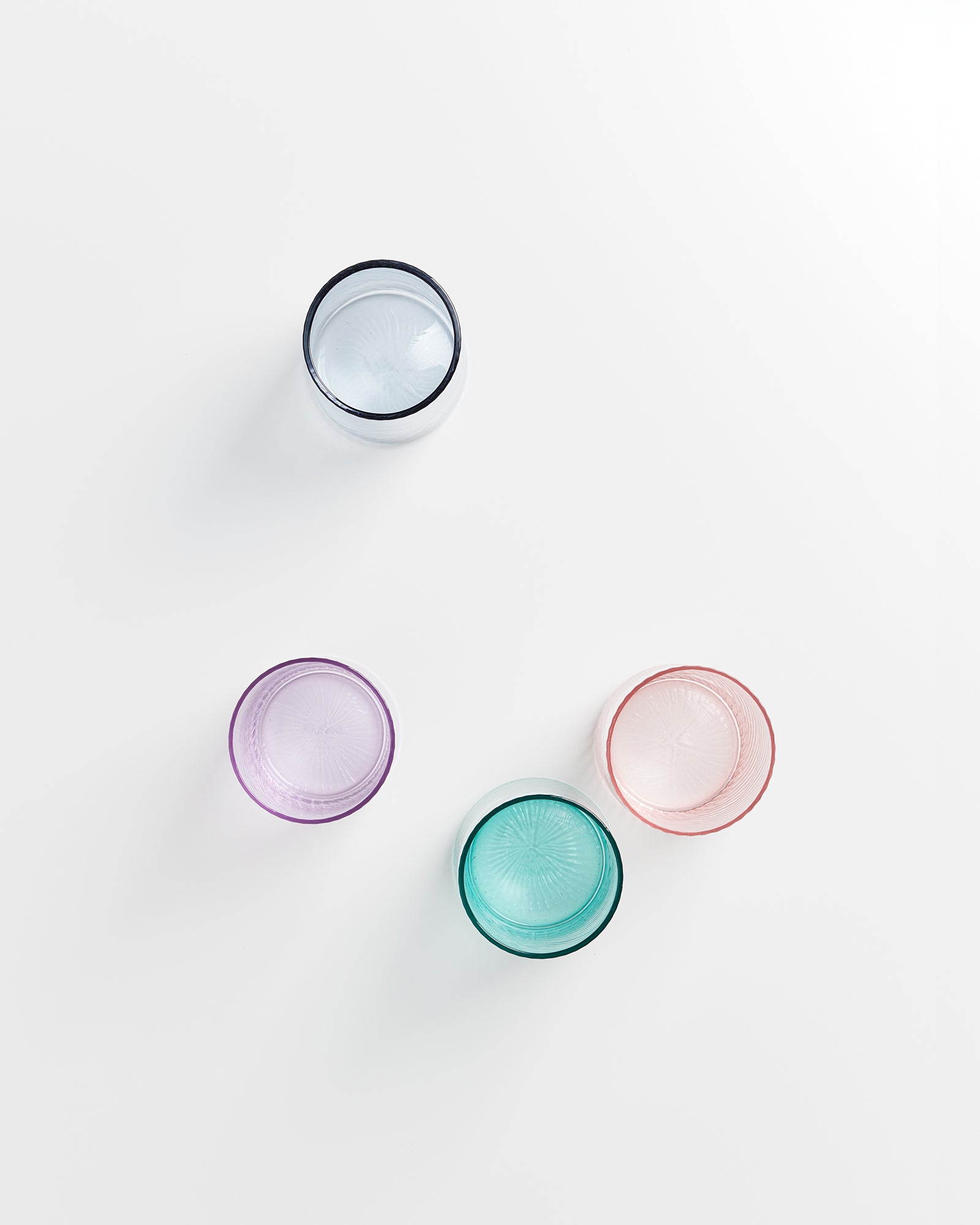 Vier bunte Gläser in verschiedenen Farben auf einem weißen Hintergrund.