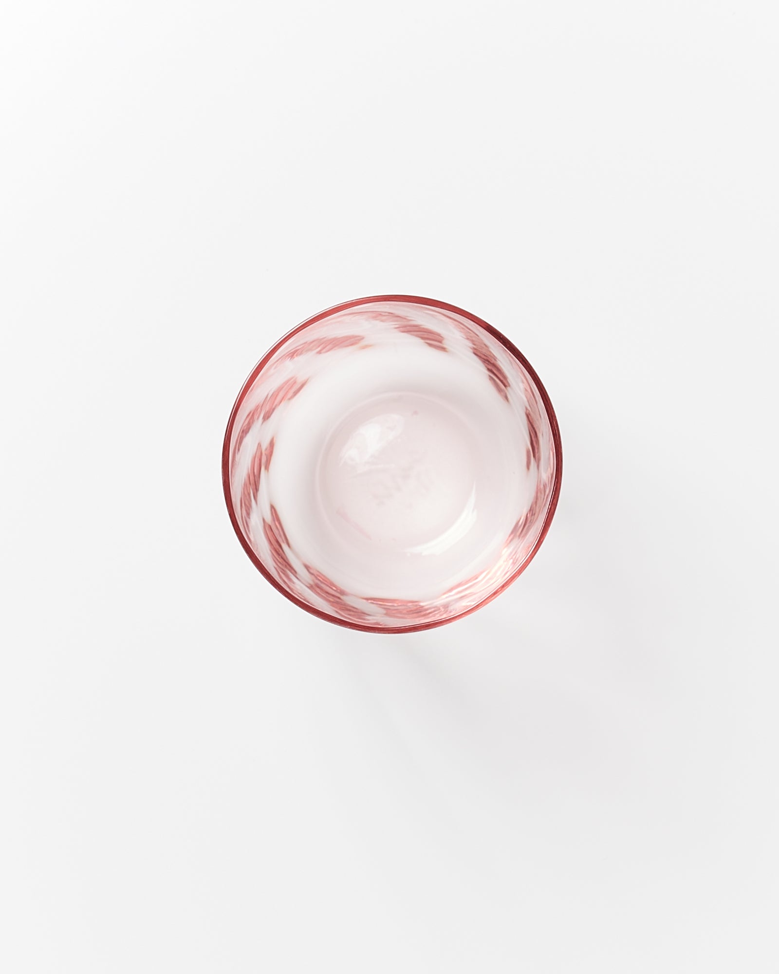 Runde Schüssel mit rotem, gewelltem Muster auf weißem Hintergrund von oben gesehen.