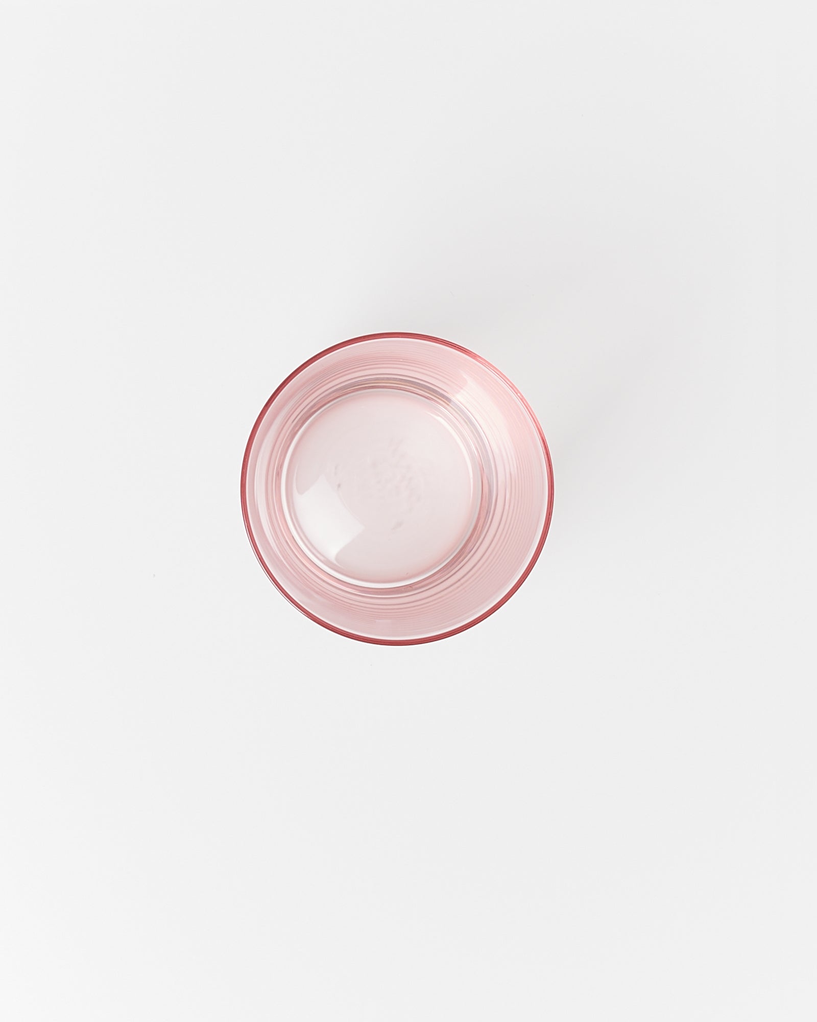 Rosa, transparente Glasschale auf weißem Hintergrund von oben gesehen.