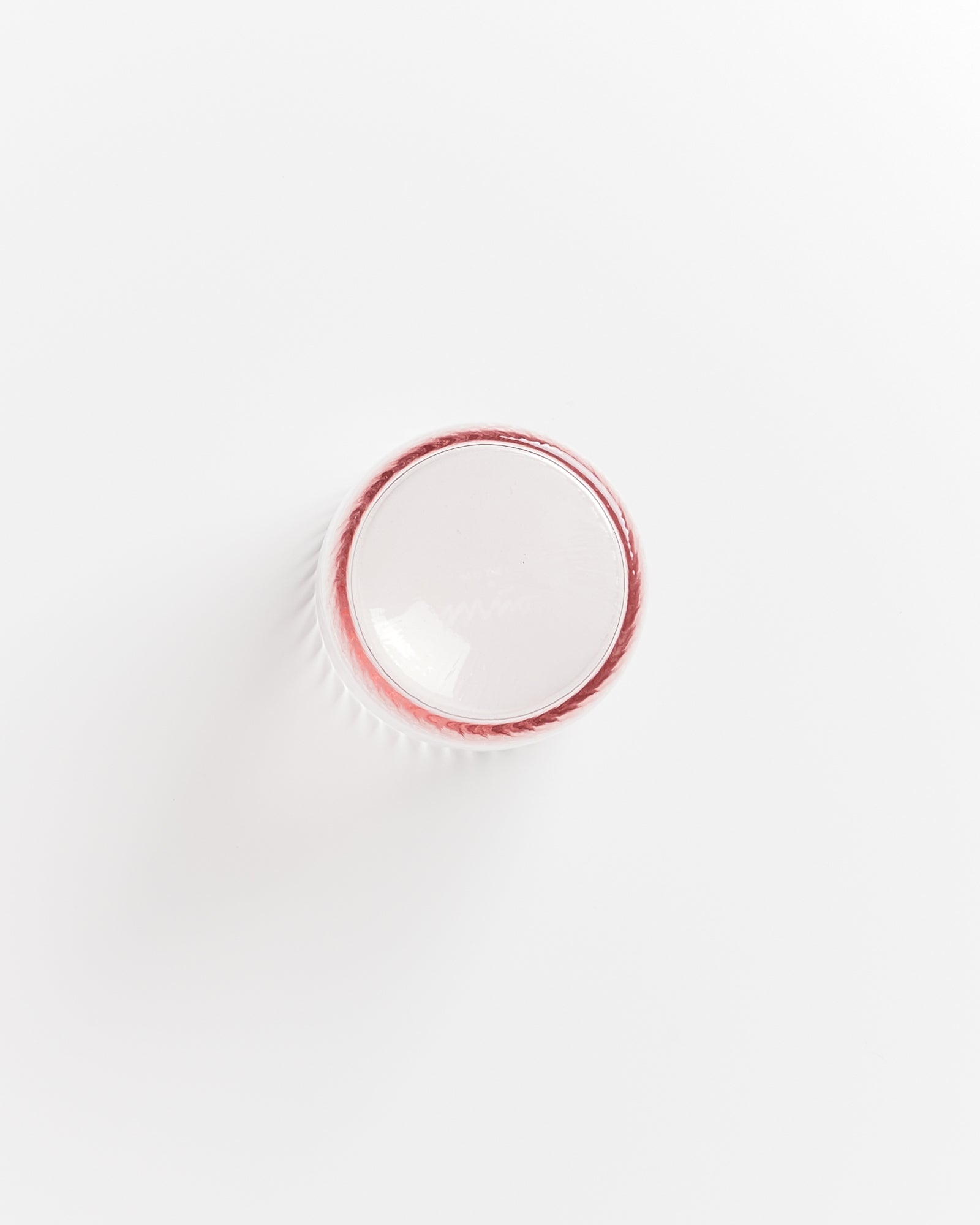 Weiße Kunststoffkappe mit rotem Rand aus der Vogelperspektive auf weißem Hintergrund.