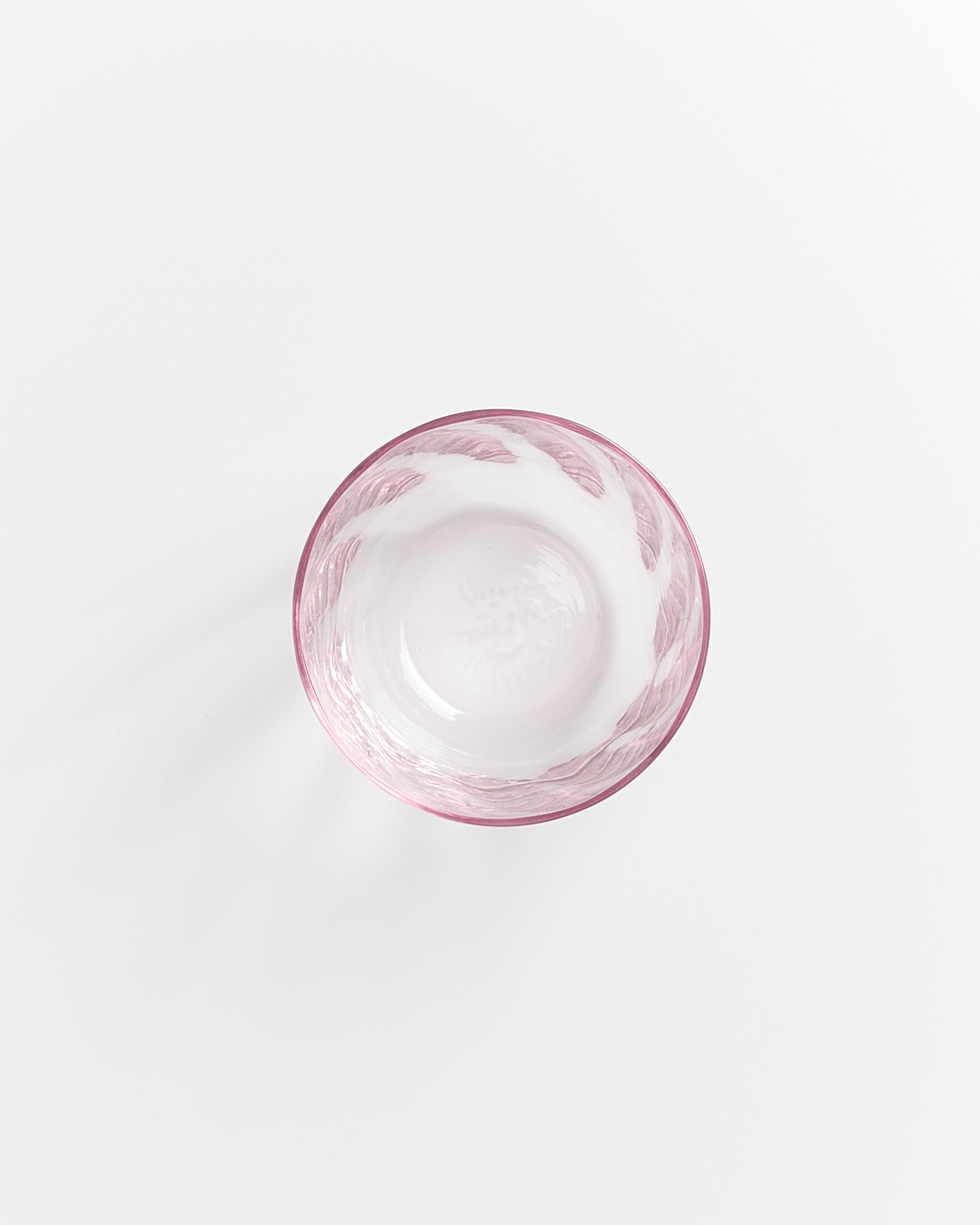 Rosa Glasschale auf weißem Hintergrund, von oben fotografiert.