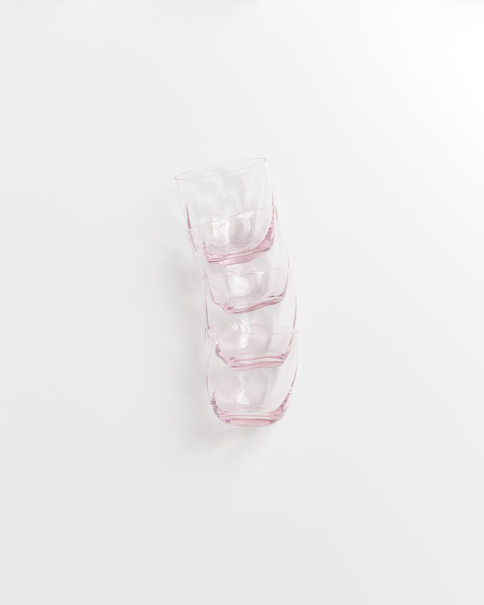 Vier gestapelte, leicht rosa Gläser auf weißem Hintergrund.