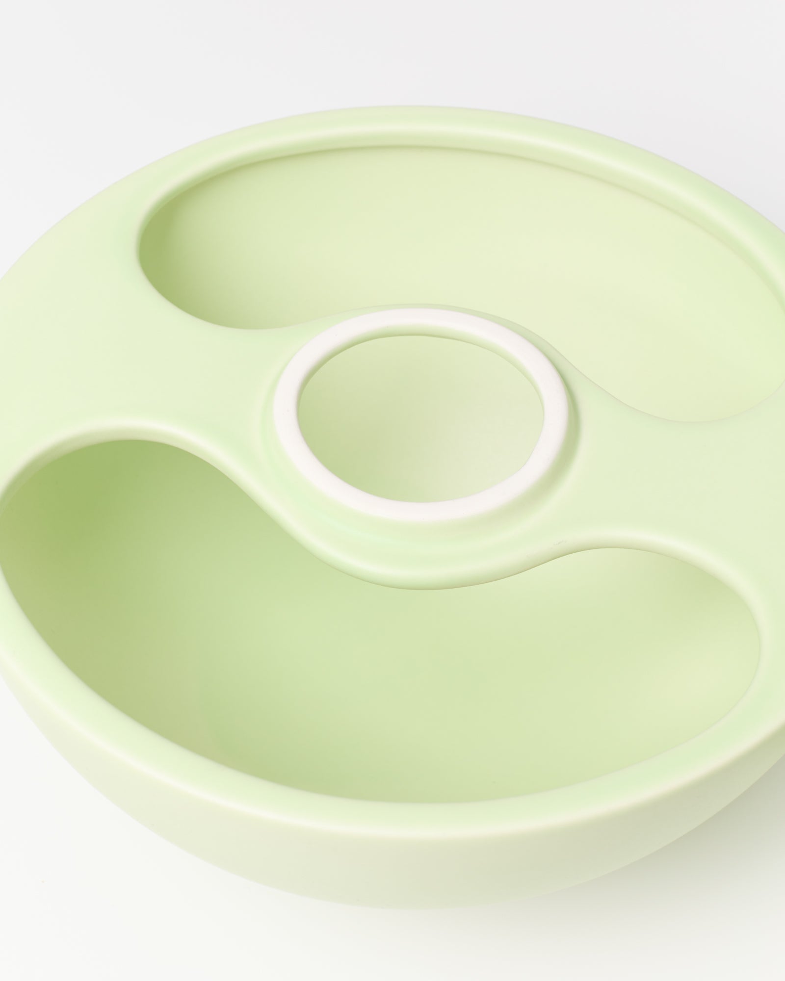 Hellgrüne Schüssel mit mehreren Fächern und einem runden Griff in der Mitte auf weißem Hintergrund.