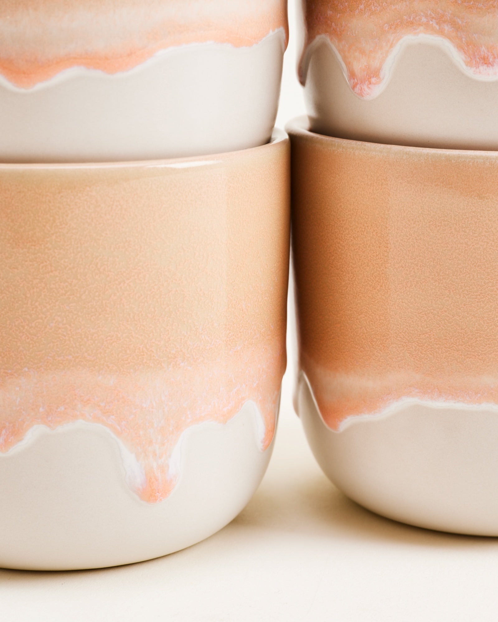 Nahaufnahme von stapelbaren Keramikschalen mit pastellfarbenem, wellenförmigem Rand auf gefrostetem Untergrund.