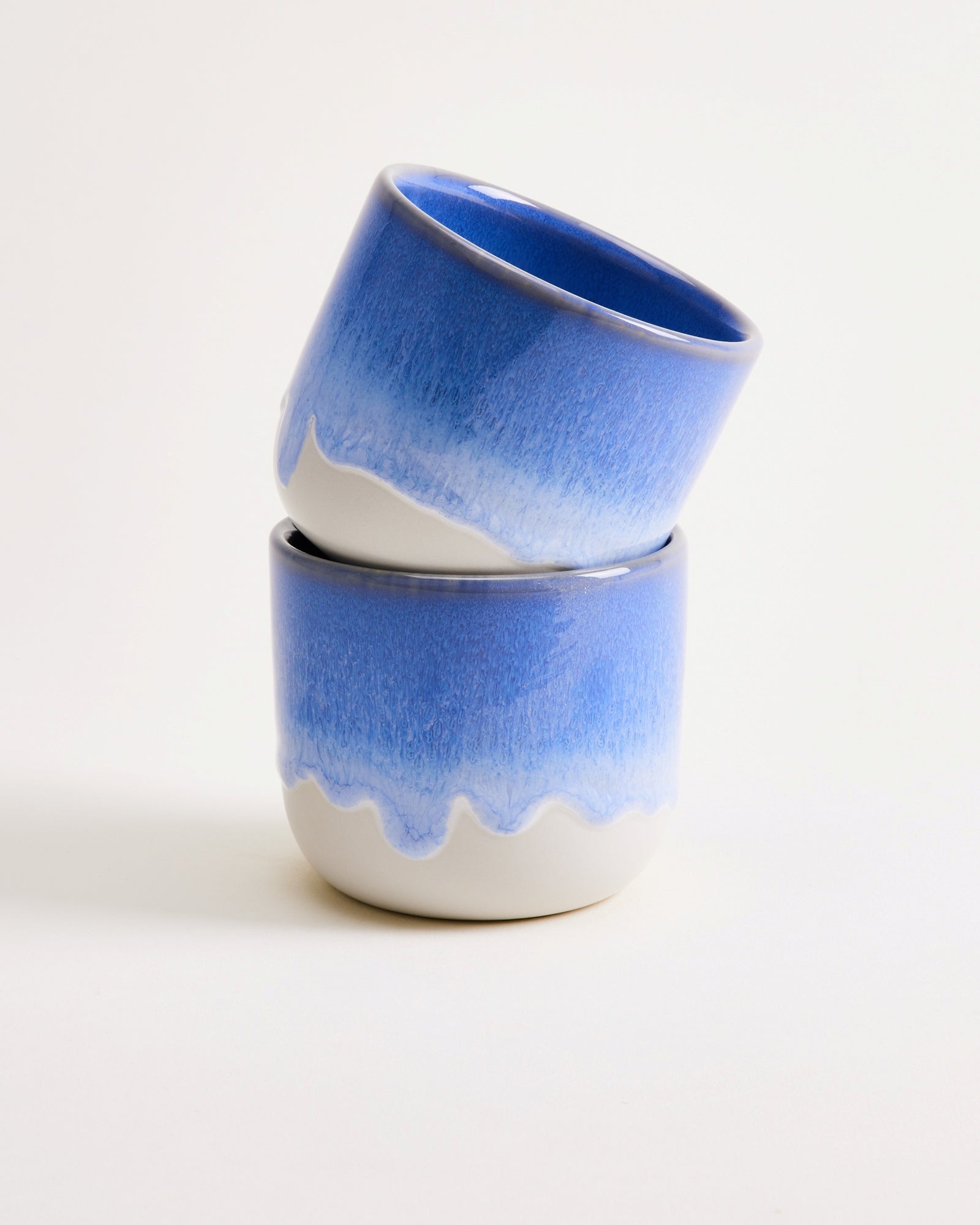 Zwei blau-weiße, ineinander gestapelte Keramikbecher vor neutralem Hintergrund.