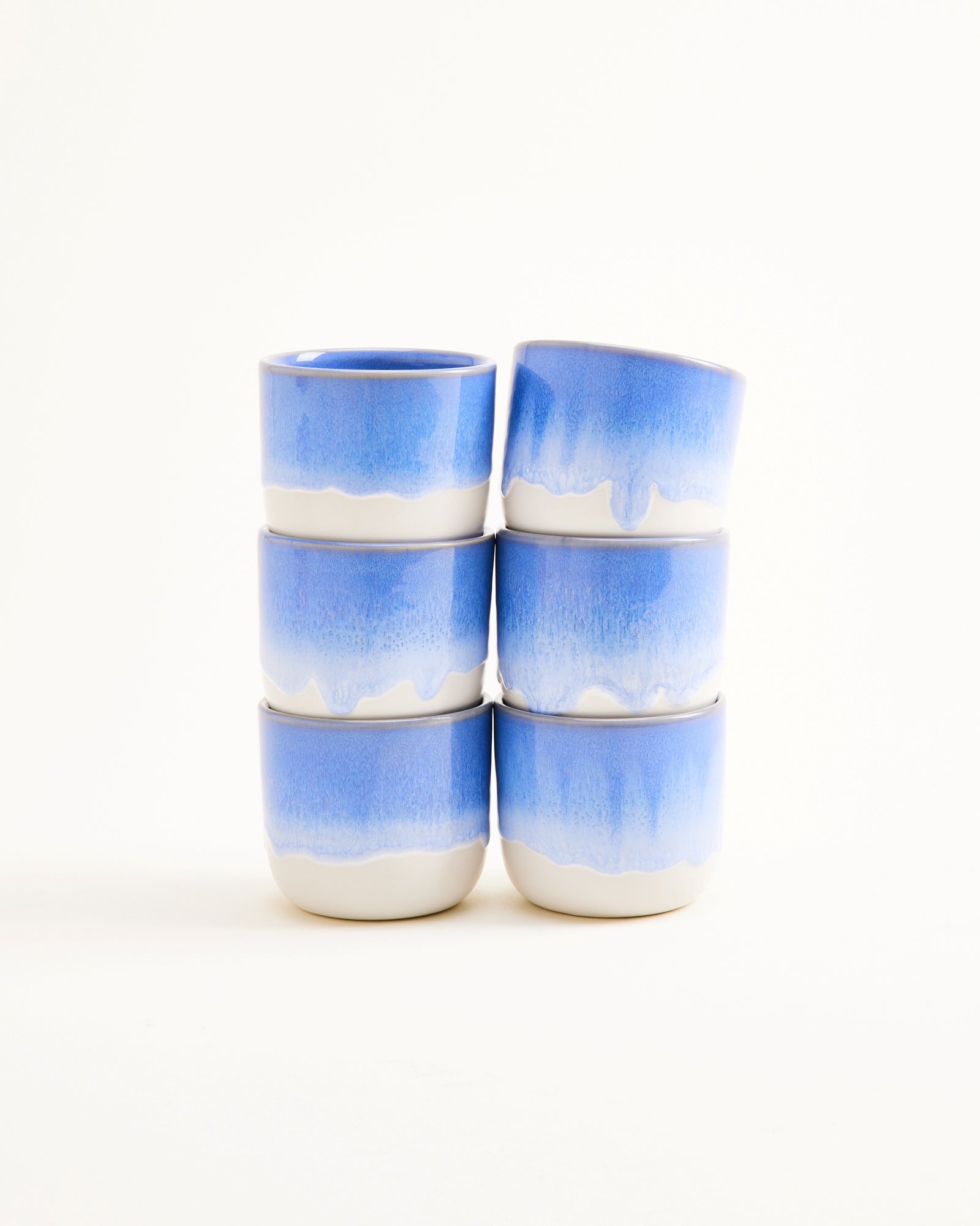 Sechs stapelbare Tassen mit blau-weißem Farbverlauf auf weißem Hintergrund.
