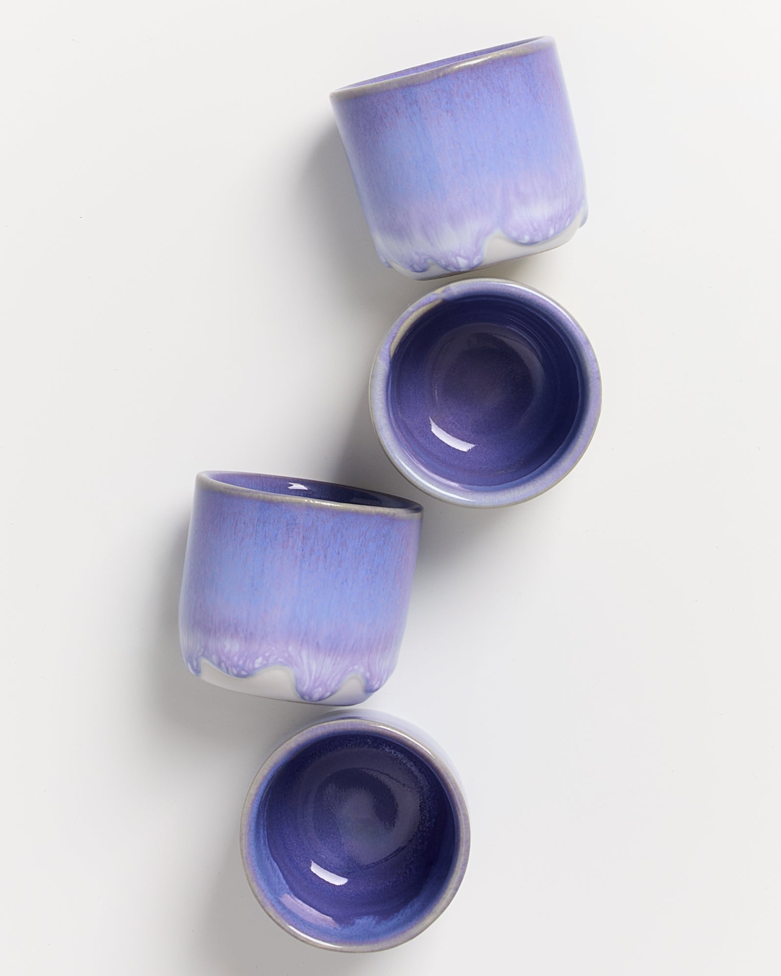 Vier lilafarbene, gläserne Schalen in einem eleganten Anordnung auf weißem Hintergrund.