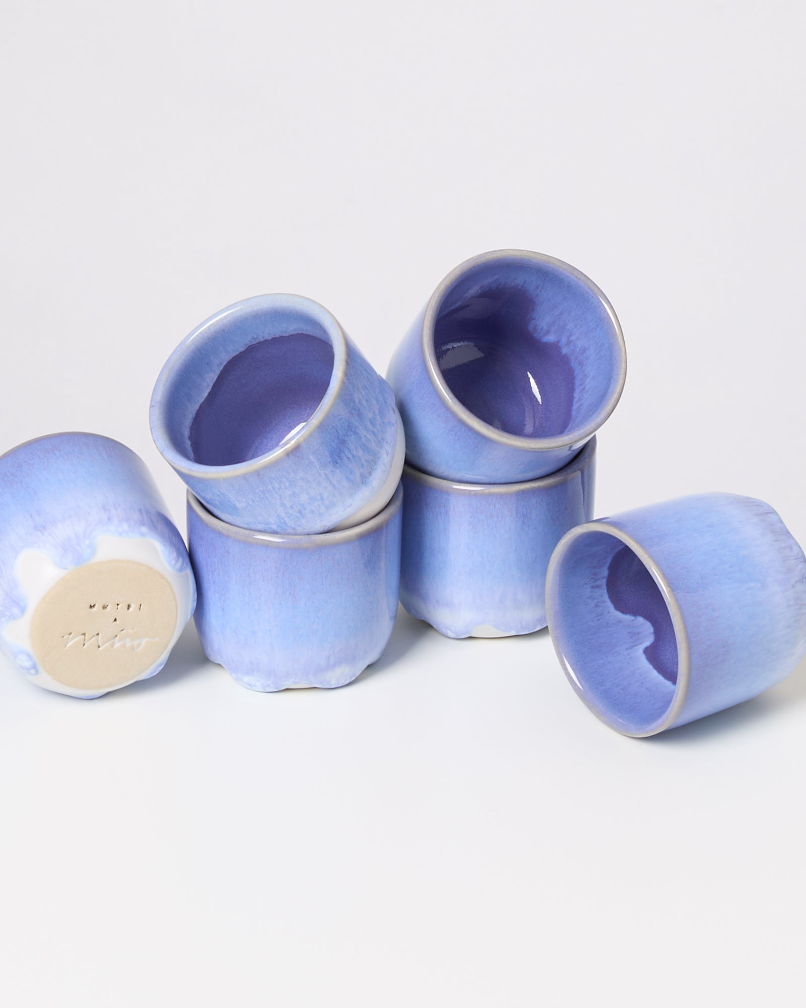 Fünf gestapelte blaue Keramikbecher auf einem weißen Hintergrund.