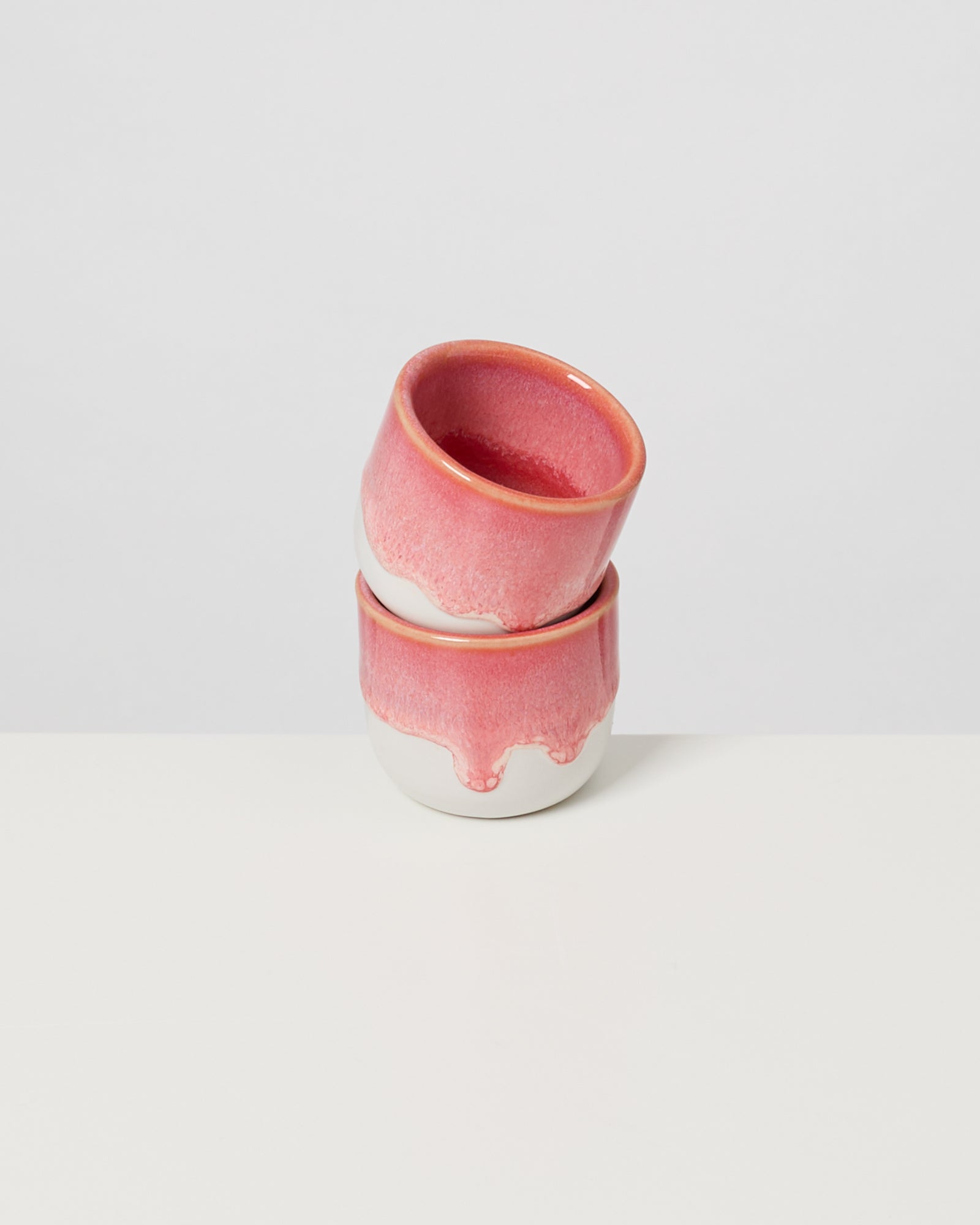 Zwei stapelbare Keramikschalen mit rosa glasierter Oberfläche auf weißem Hintergrund.