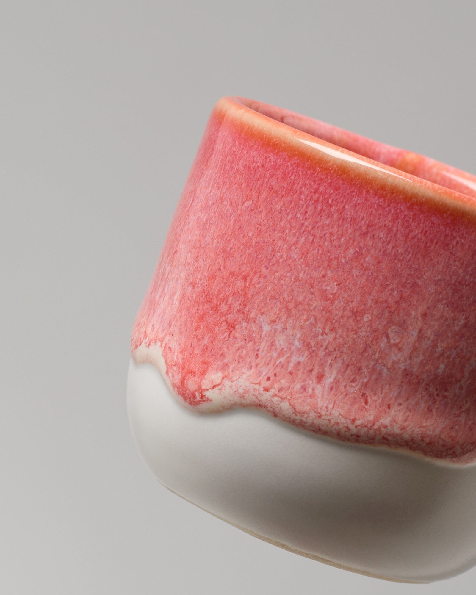 Nahaufnahme einer rosafarbenen Keramik mit weißem, gewellten Rand auf grauem Hintergrund.