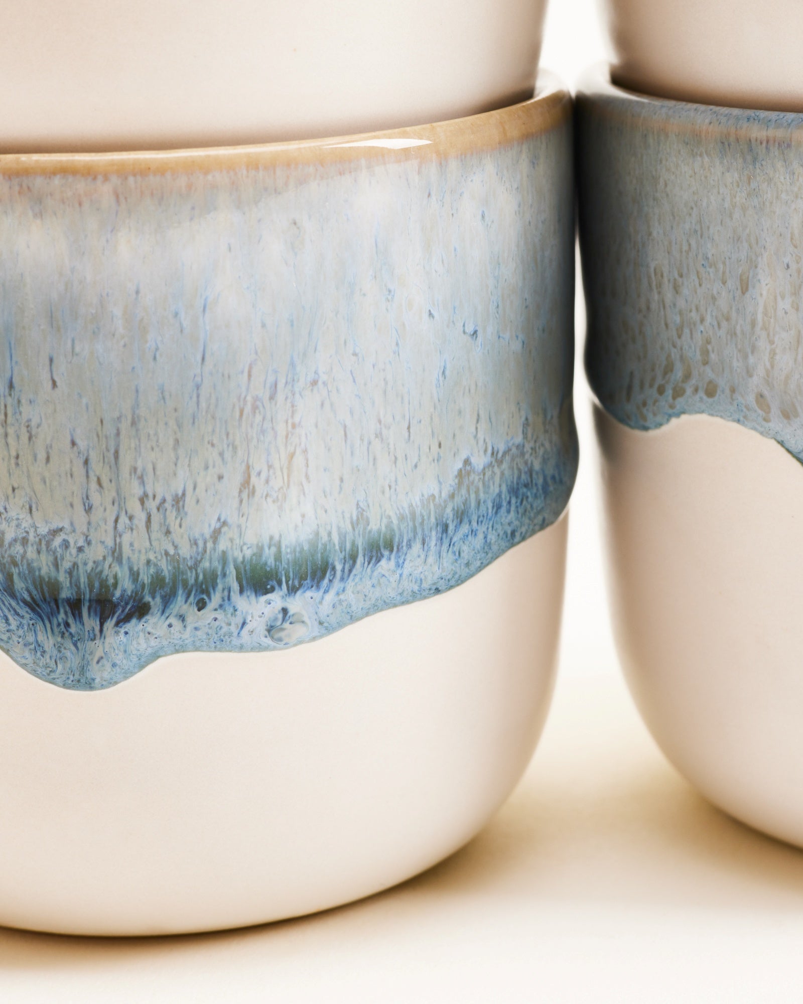 Nahaufnahme von zwei Keramiktassen mit blauer Glasur am oberen Rand.