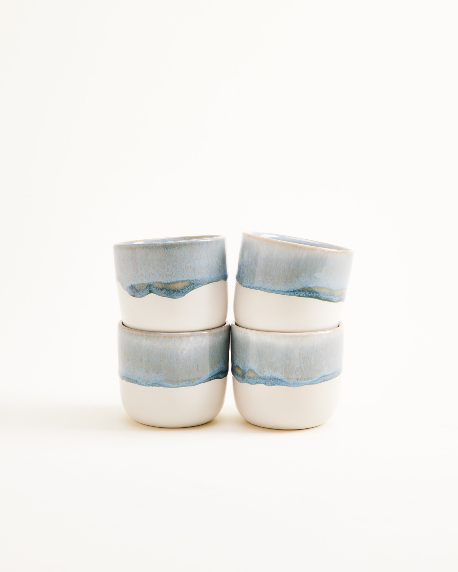 Vier stapelbare Becher mit blauem, wellenartigem Muster vor weißem Hintergrund.