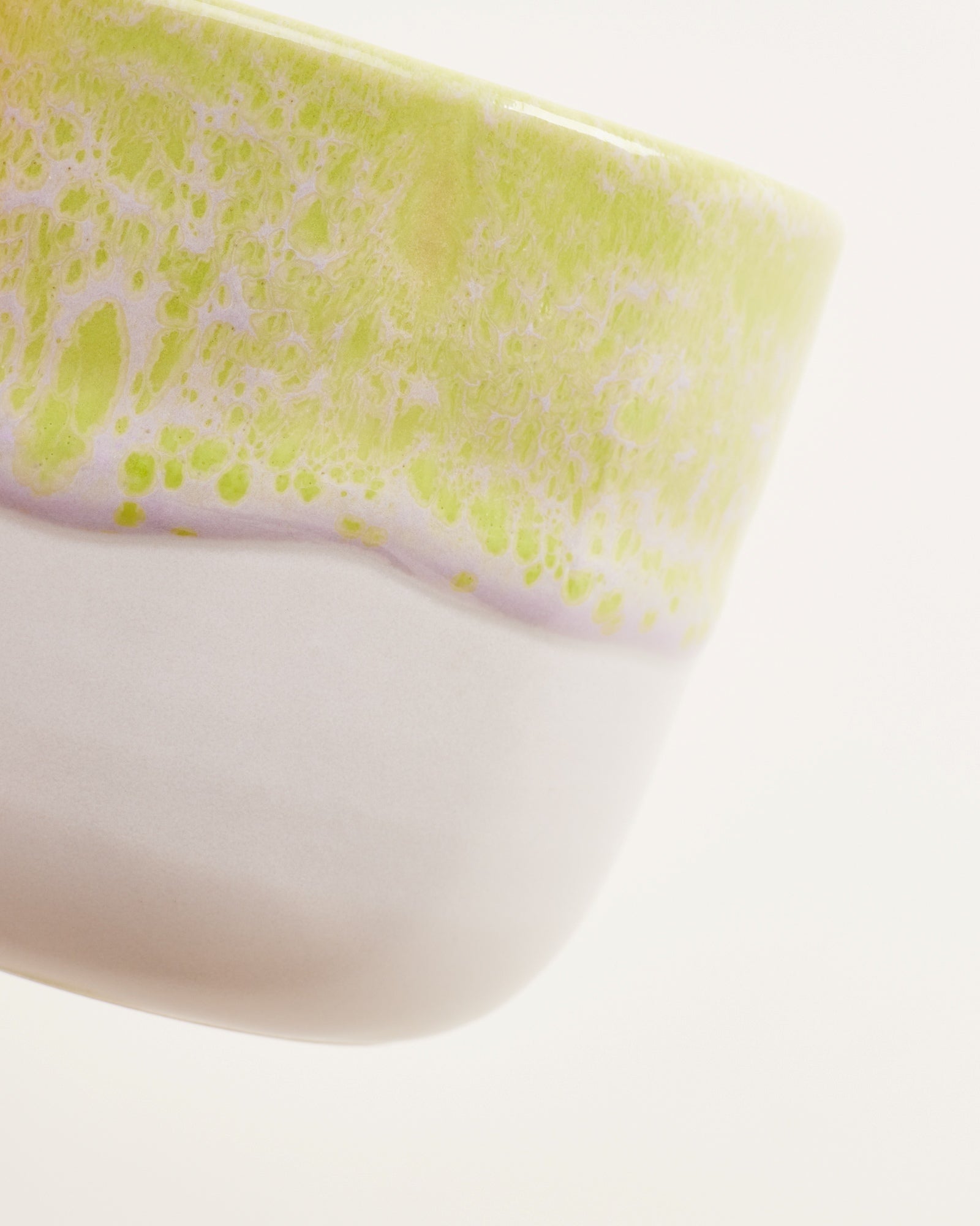 Nahaufnahme einer Keramikschale mit gelb-grünem, gesprenkeltem Muster am oberen Rand.