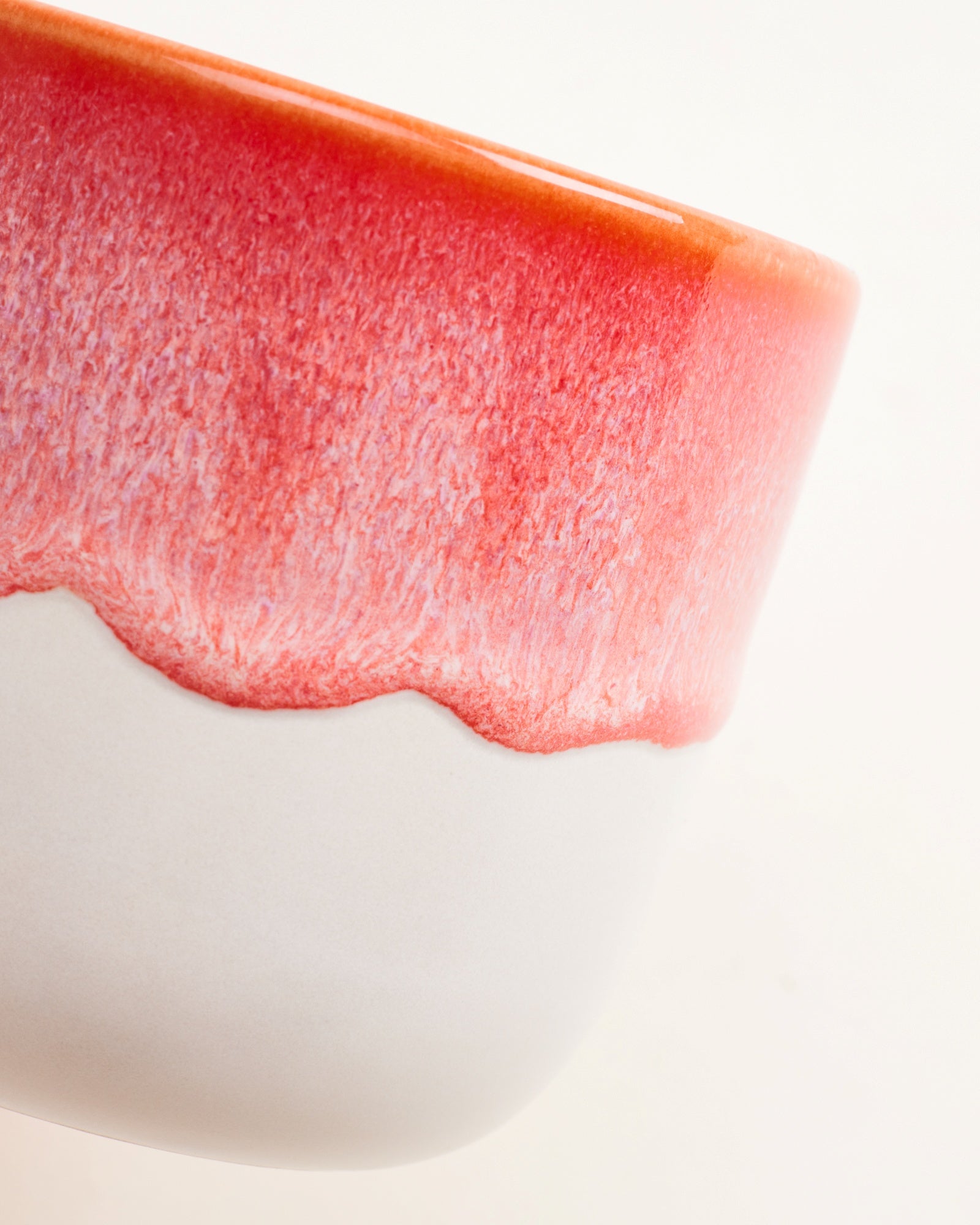Nahaufnahme eines rot-weißen, keramikähnlichen Bechers mit glatter Textur und fließendem Farbverlauf.