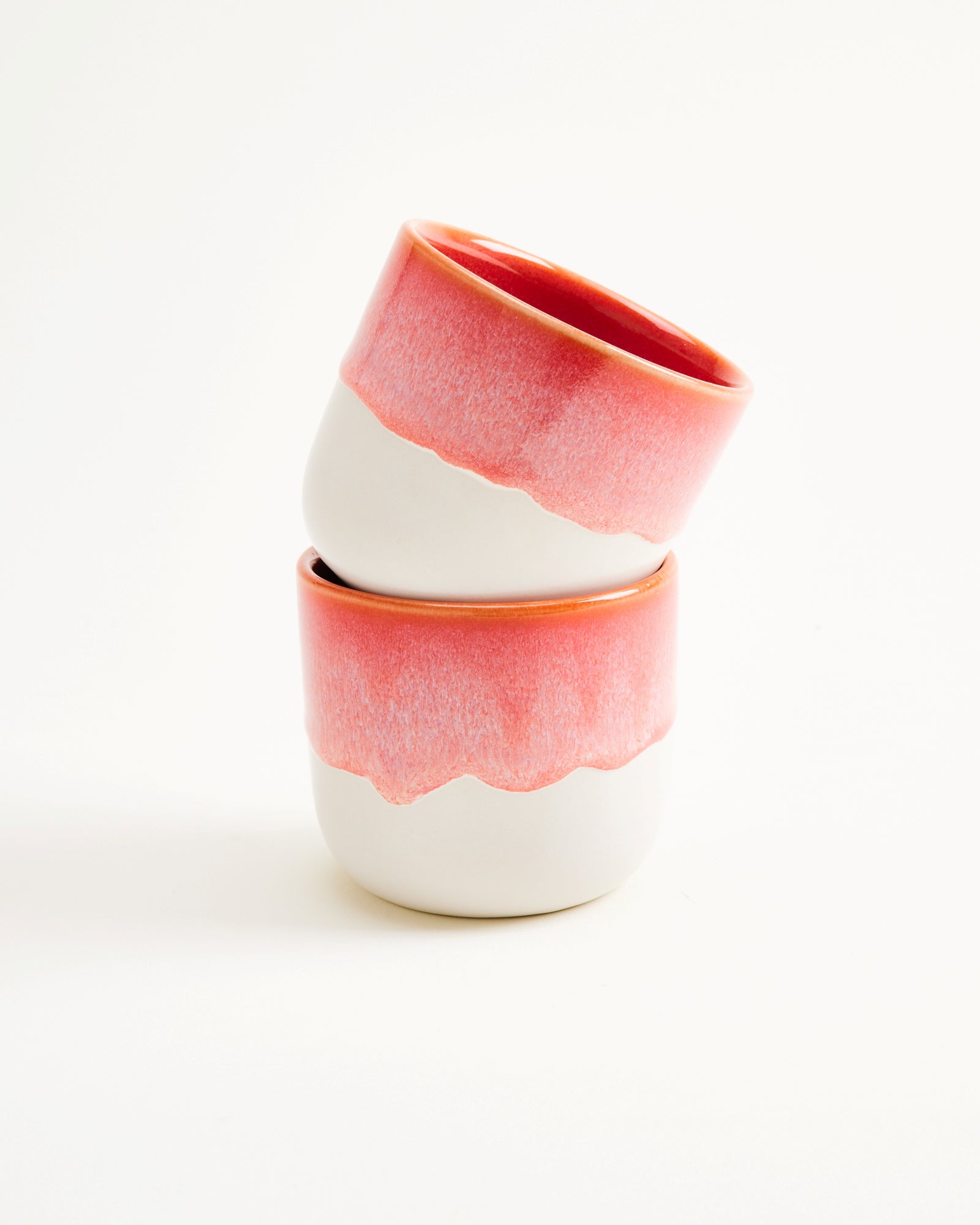 Zwei stapelbare Keramikbecher mit rotem Oberteil auf weißem Hintergrund.