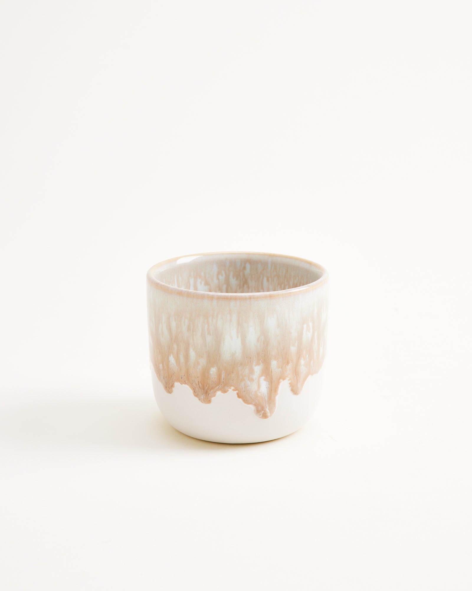 Keramikbecher mit braun-weißer Glasur auf weißem Hintergrund.