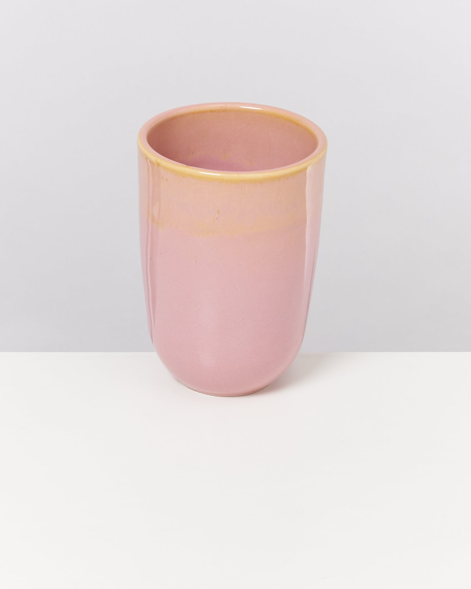 Rosa Keramikbecher mit glatter Oberfläche auf weißem Hintergrund.