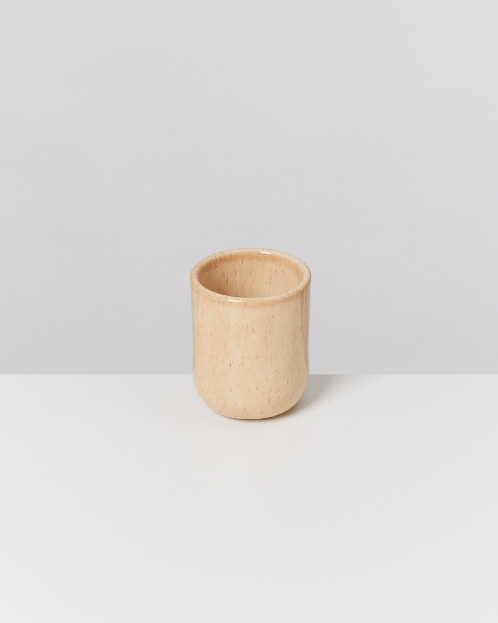 Becher in Naturton steht auf weißem Hintergrund.