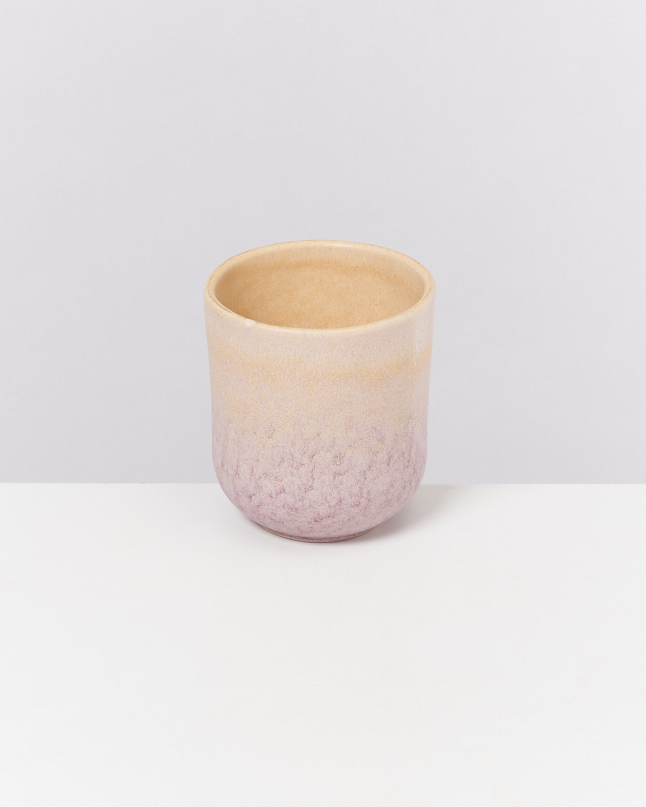 Becher mit Farbverlauf von Beige zu Lila auf einem weißen Hintergrund.