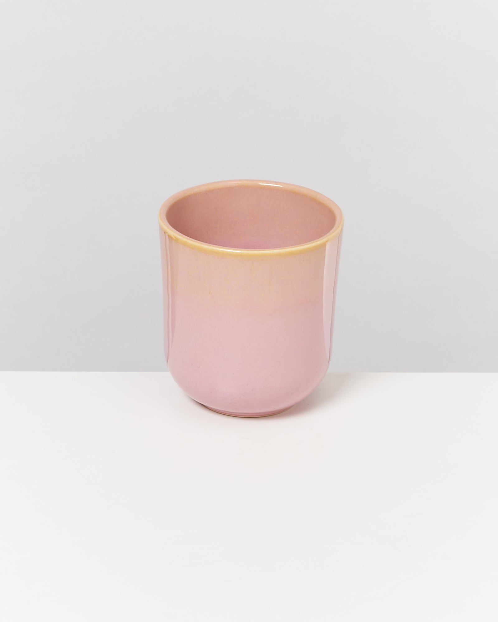 Rosa Keramikbecher auf weißem Hintergrund.