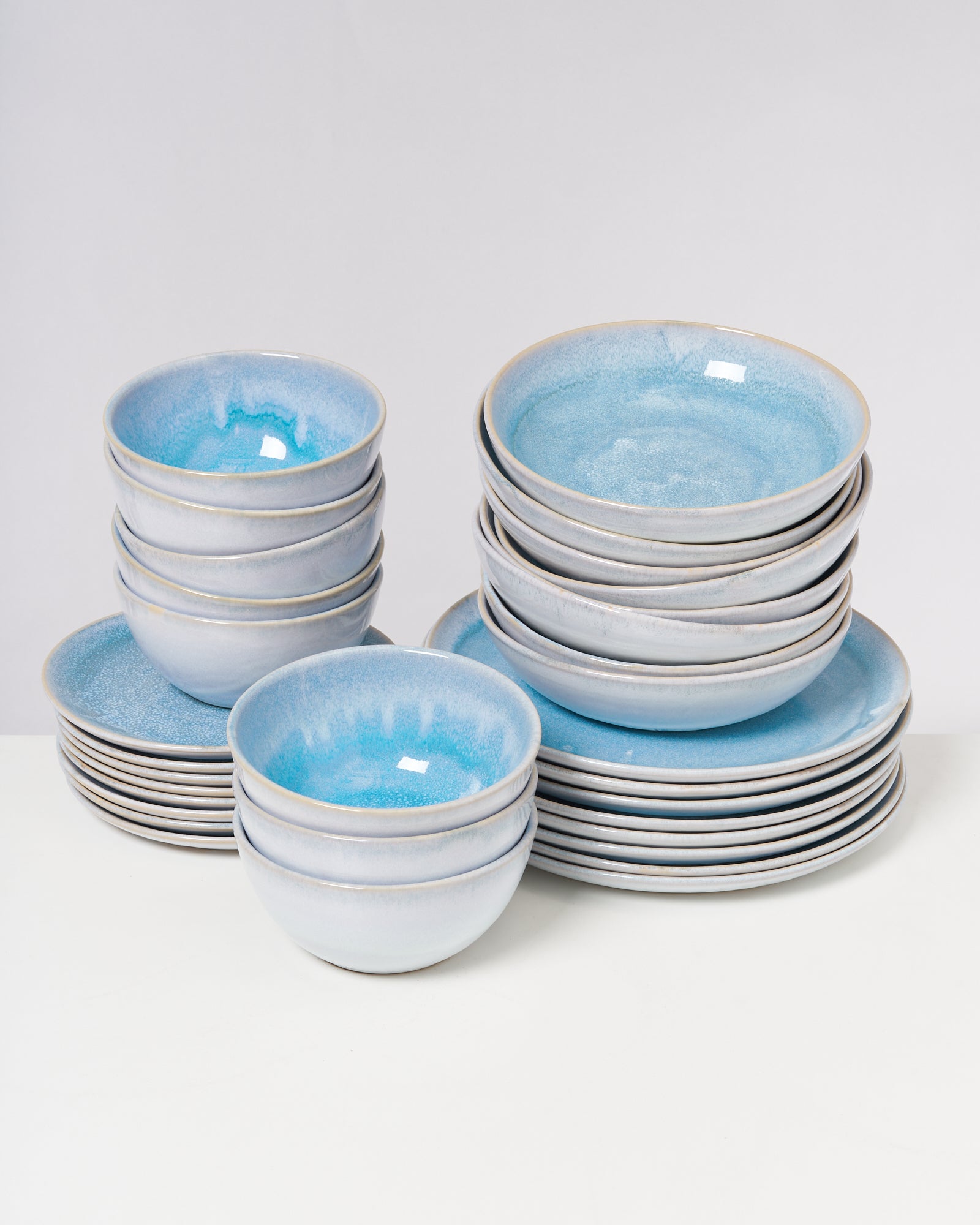 Ein Stapel blauer Keramikteller und -schüsseln auf einem weißen Hintergrund.