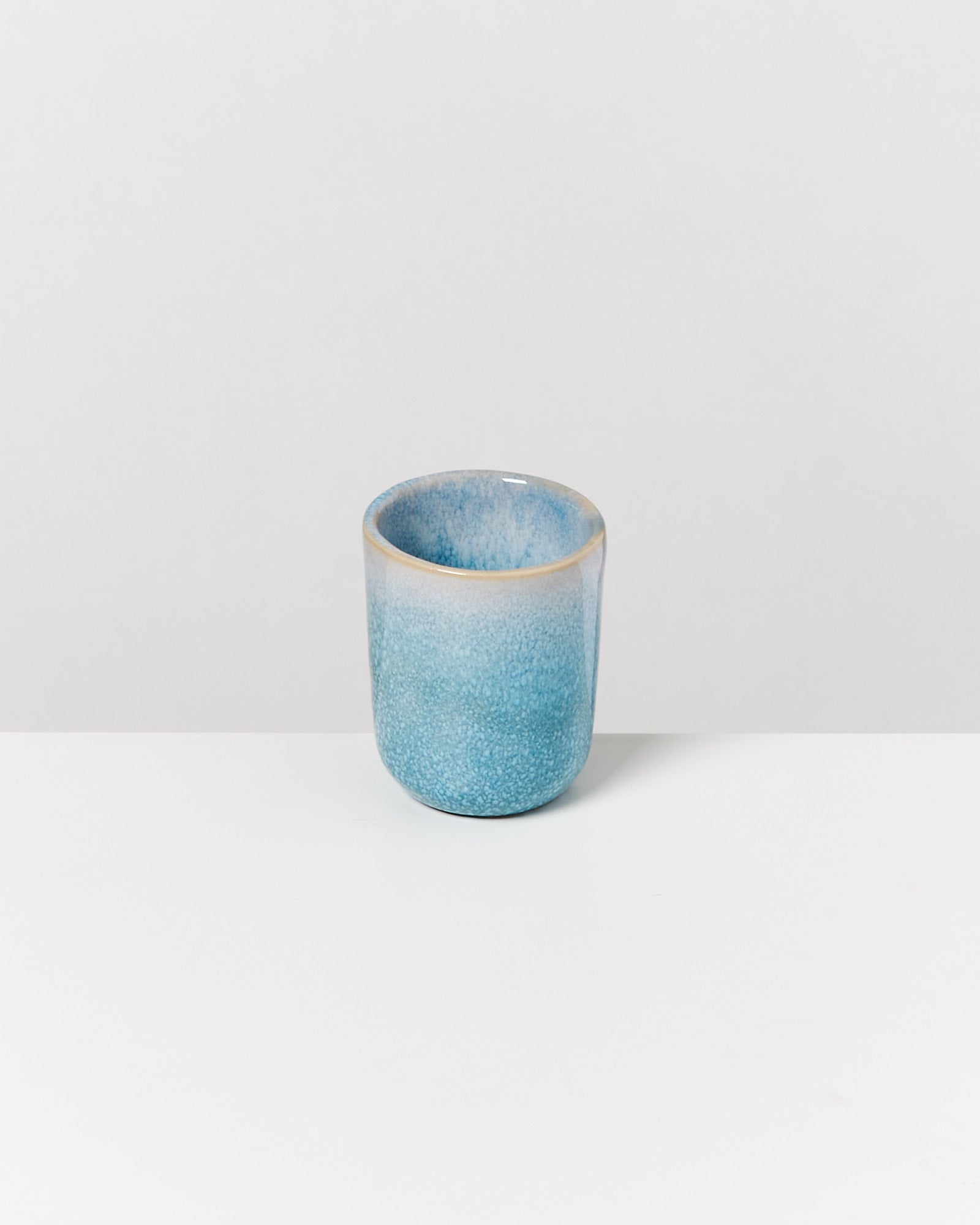 Blaue, keramikartige Tasse mit Struktur auf einem weißen Hintergrund.