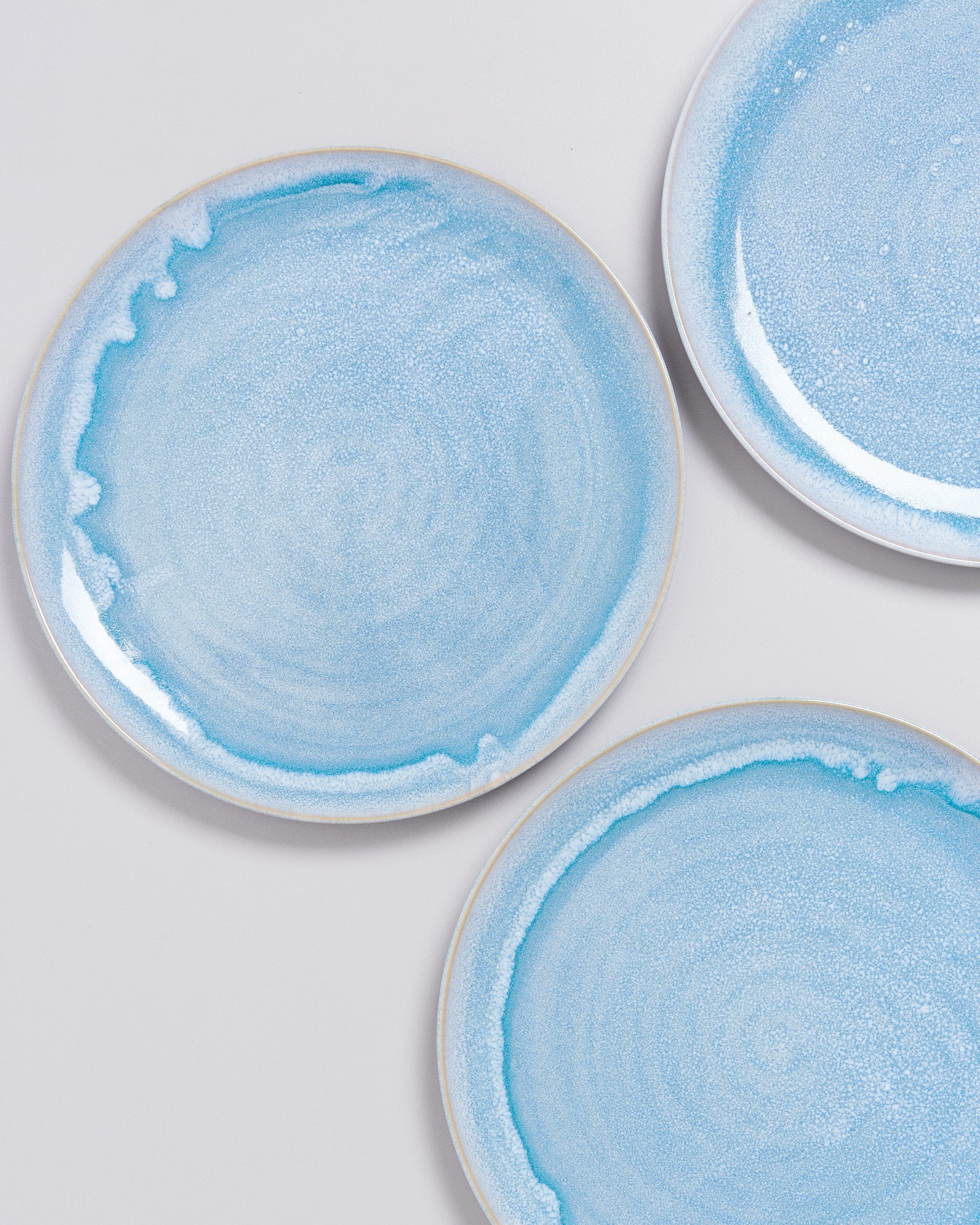 Drei blaue Keramikteller mit texturierter Oberfläche auf hellem Hintergrund.