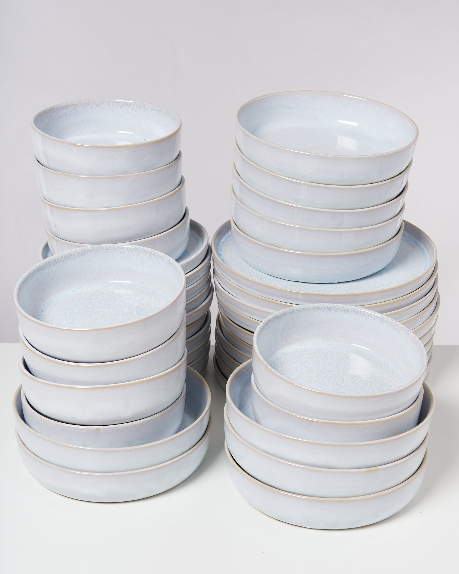 Mehrere Stapel hellblauer, runder Schüsseln auf einer weißen Oberfläche.