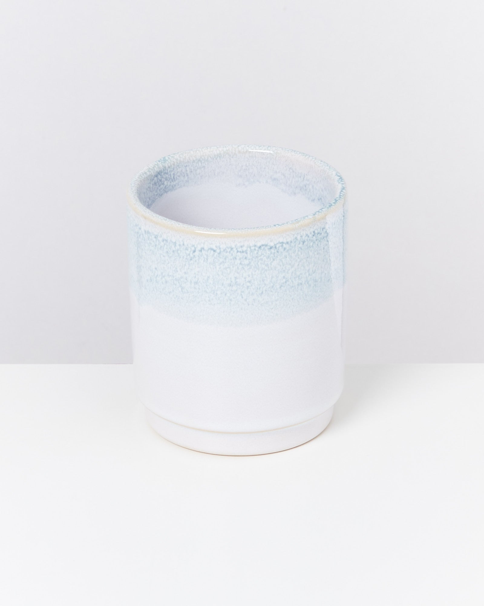 Weiße und hellblaue Keramikvase auf einem weißen Hintergrund.