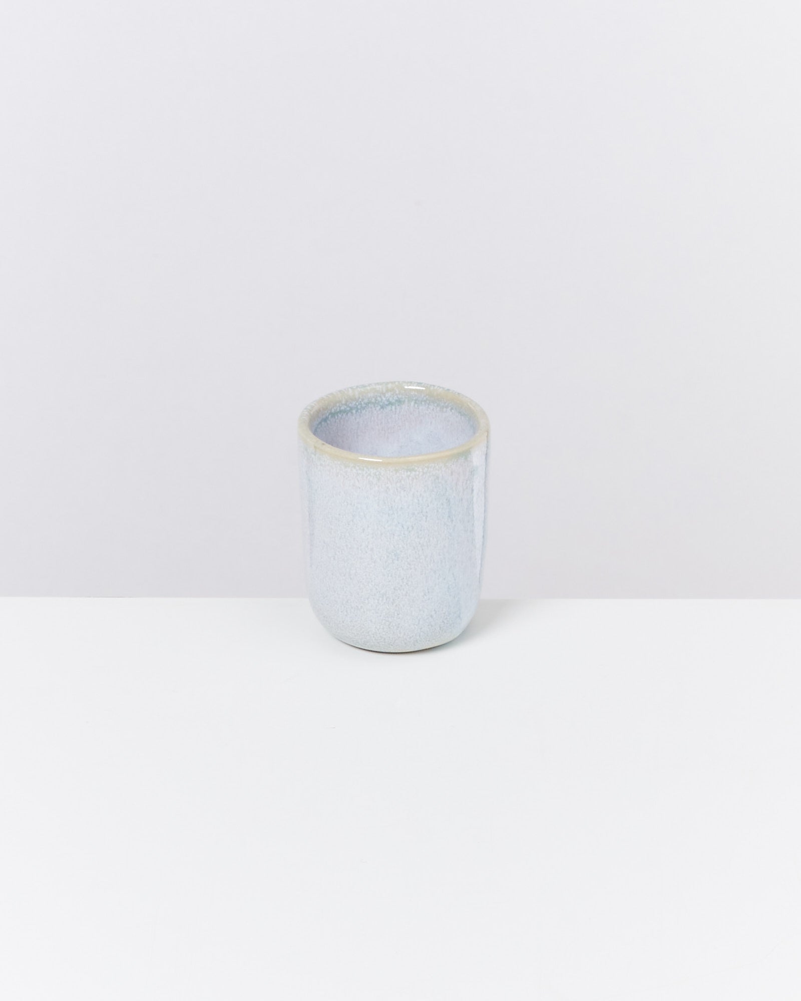 Kleine, hellblaue keramische Tasse auf weißem Hintergrund.