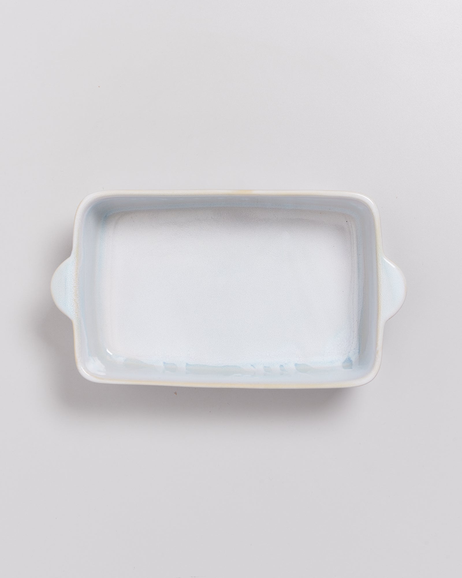 Rechteckige, weiße Keramik-Backform mit zwei Henkeln auf weißem Hintergrund.