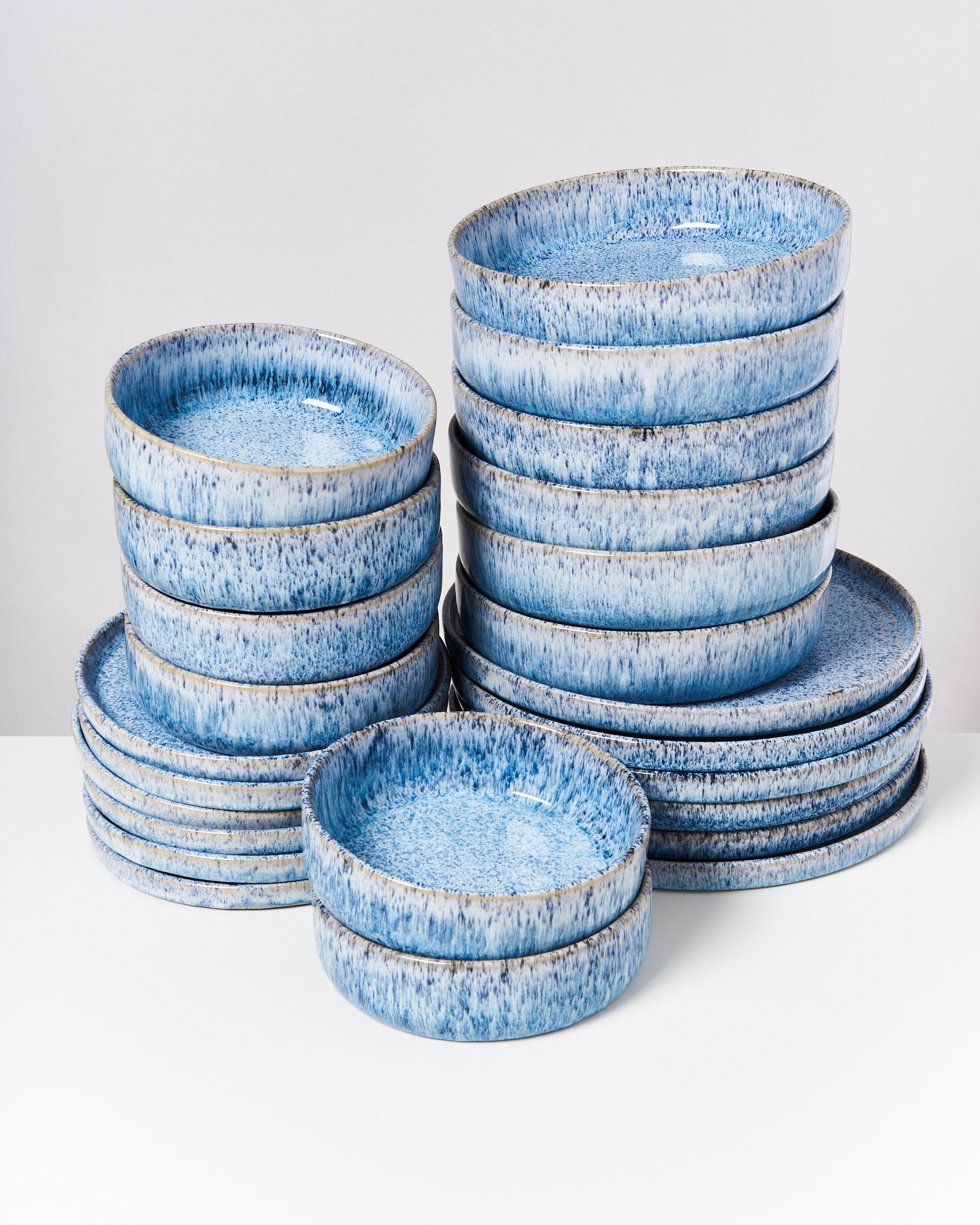 Stapel aus blauen Keramiktellern mit gesprenkeltem Muster auf weißem Hintergrund.