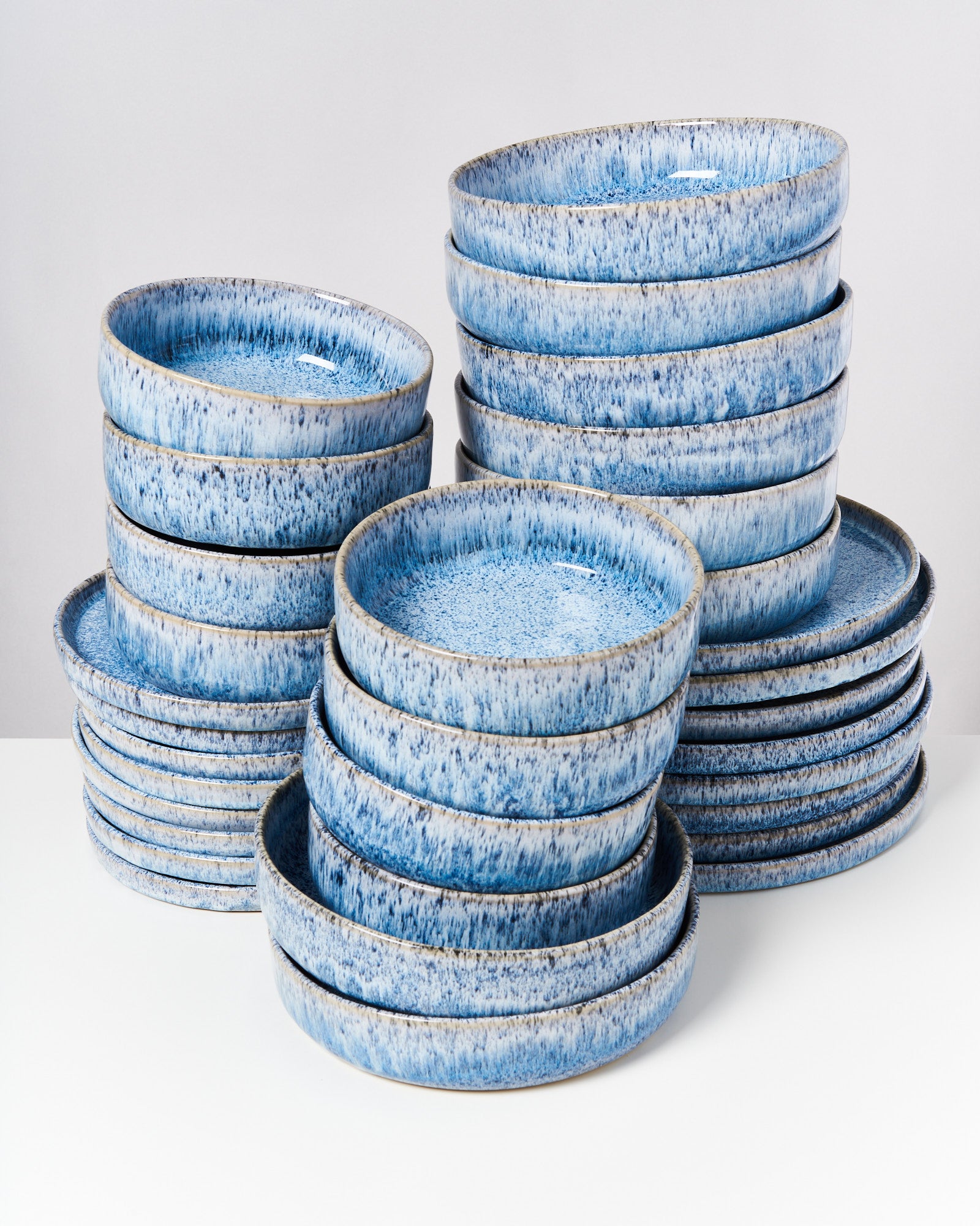 Stapel von blauen, gesprenkelten Keramiktellern auf hellem Hintergrund.