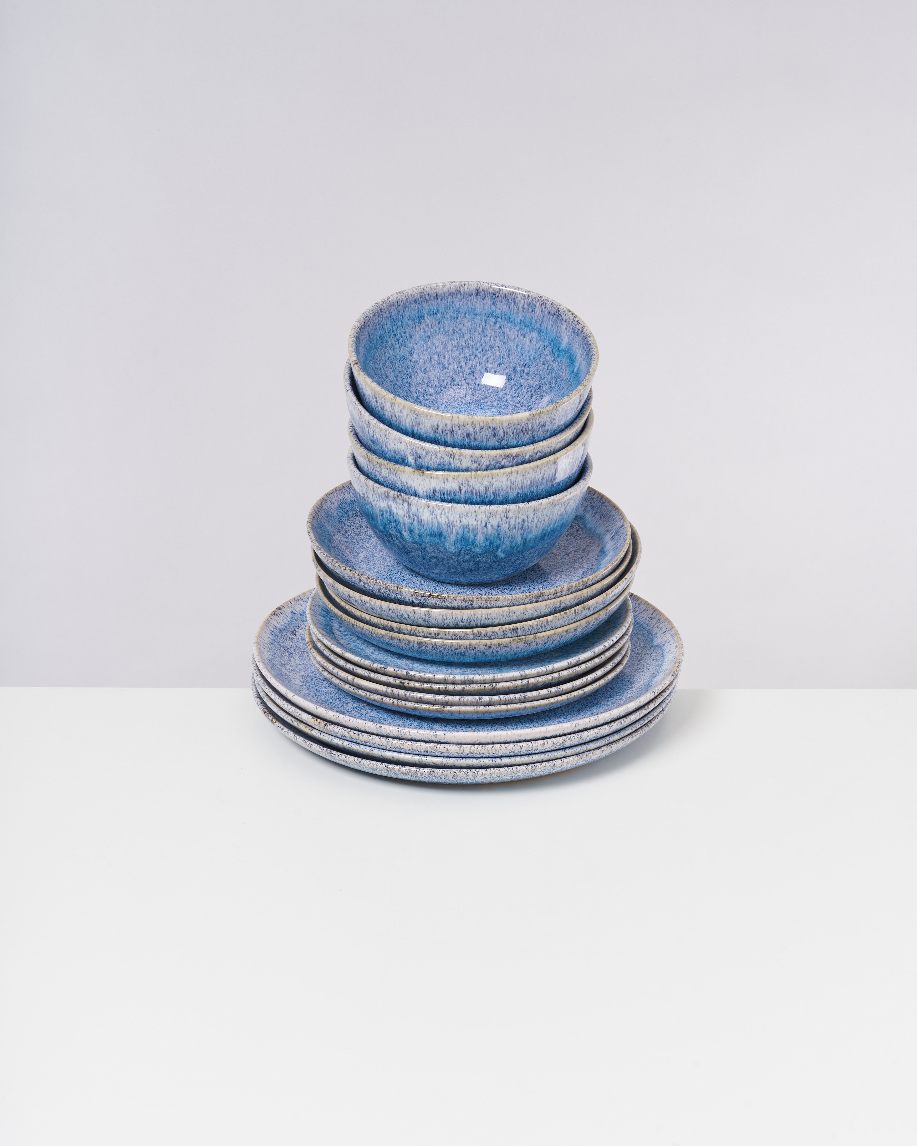 Gestapeltes Set aus blauen Schalen und Tellern auf einem weißen Hintergrund.
