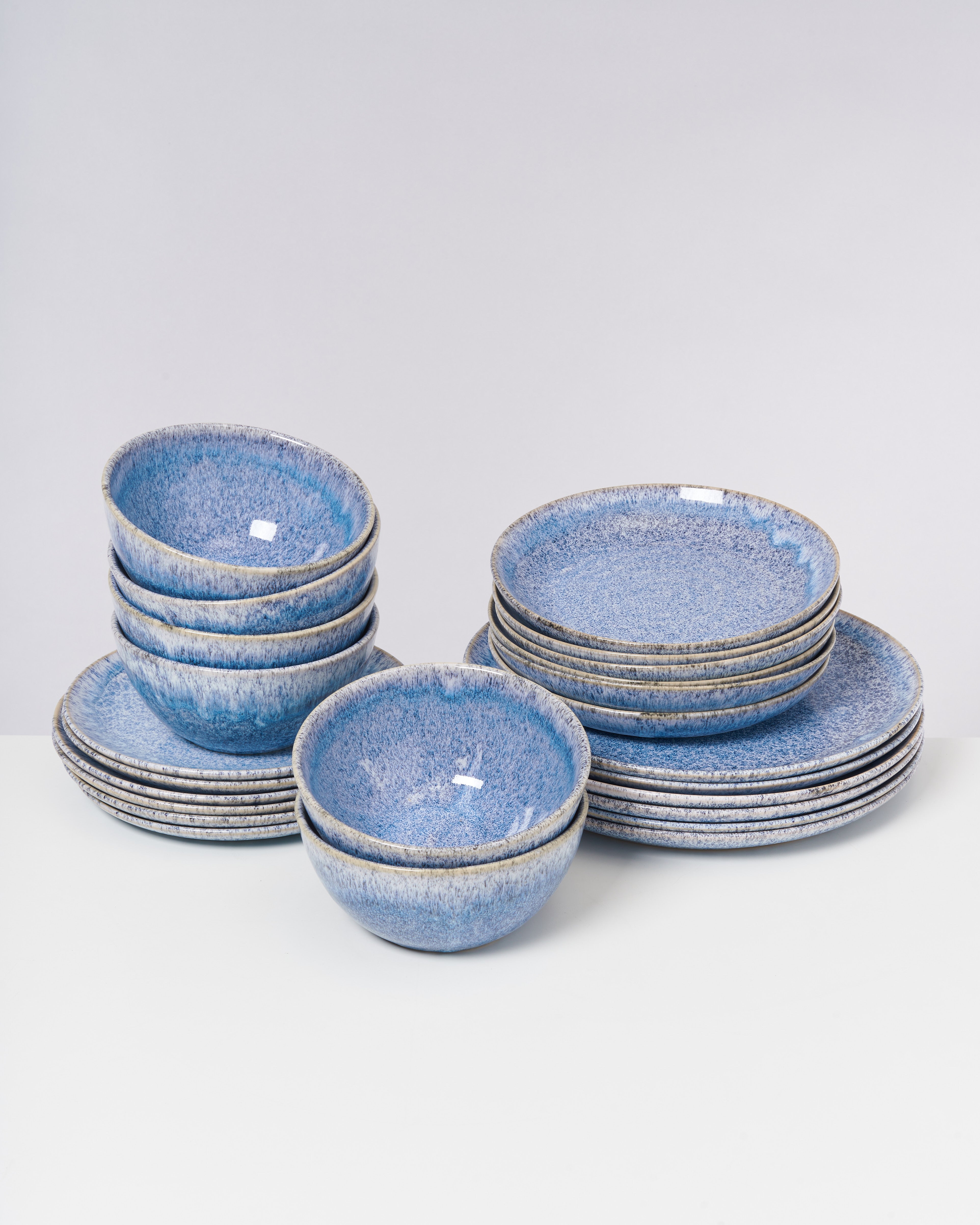 Stapel aus blauen, geäderten Tellern und Schalen auf einem weißen Hintergrund.