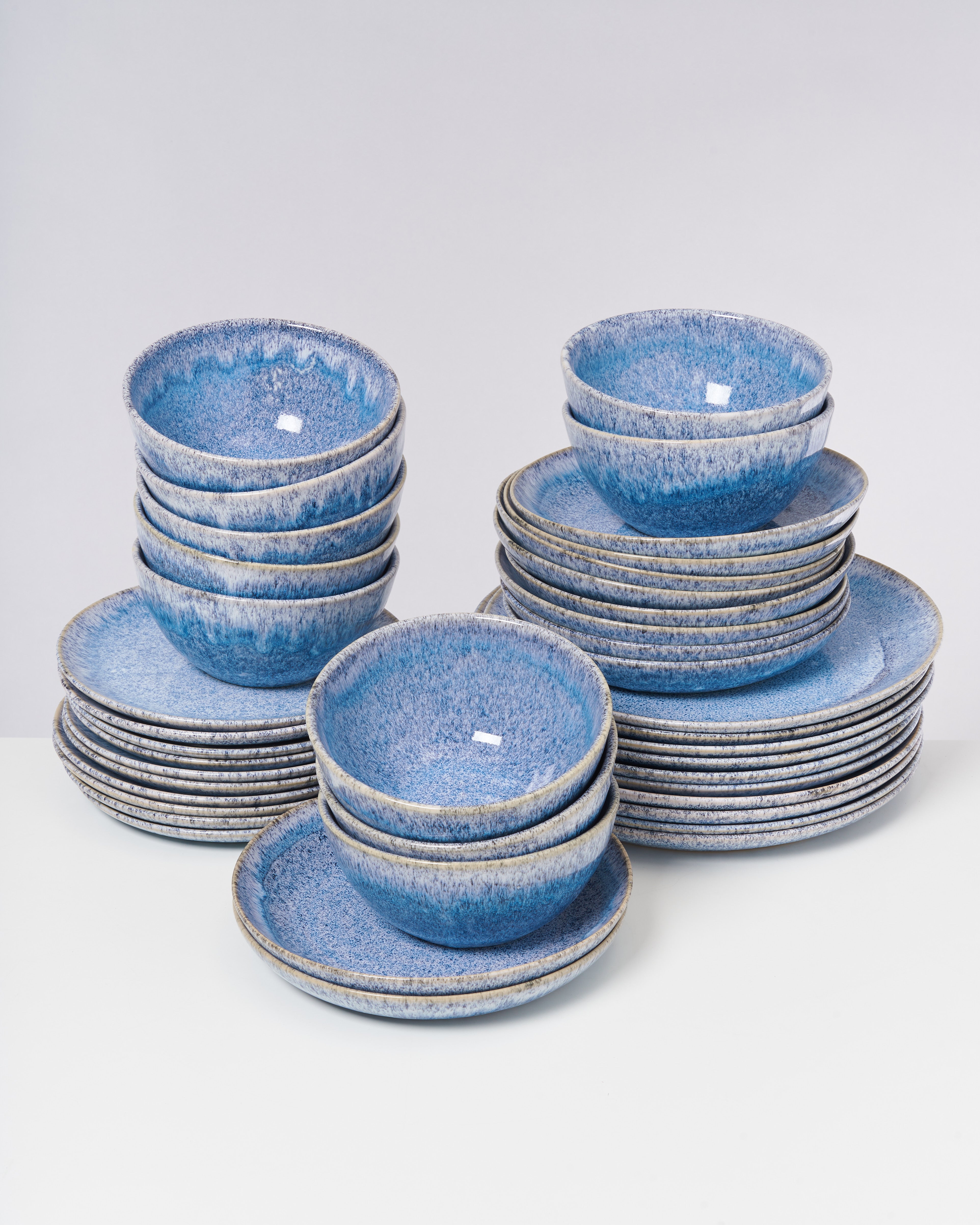 Ein Set aus blauen, glasierten Schalen und Tellern ist auf einem Tisch gestapelt.