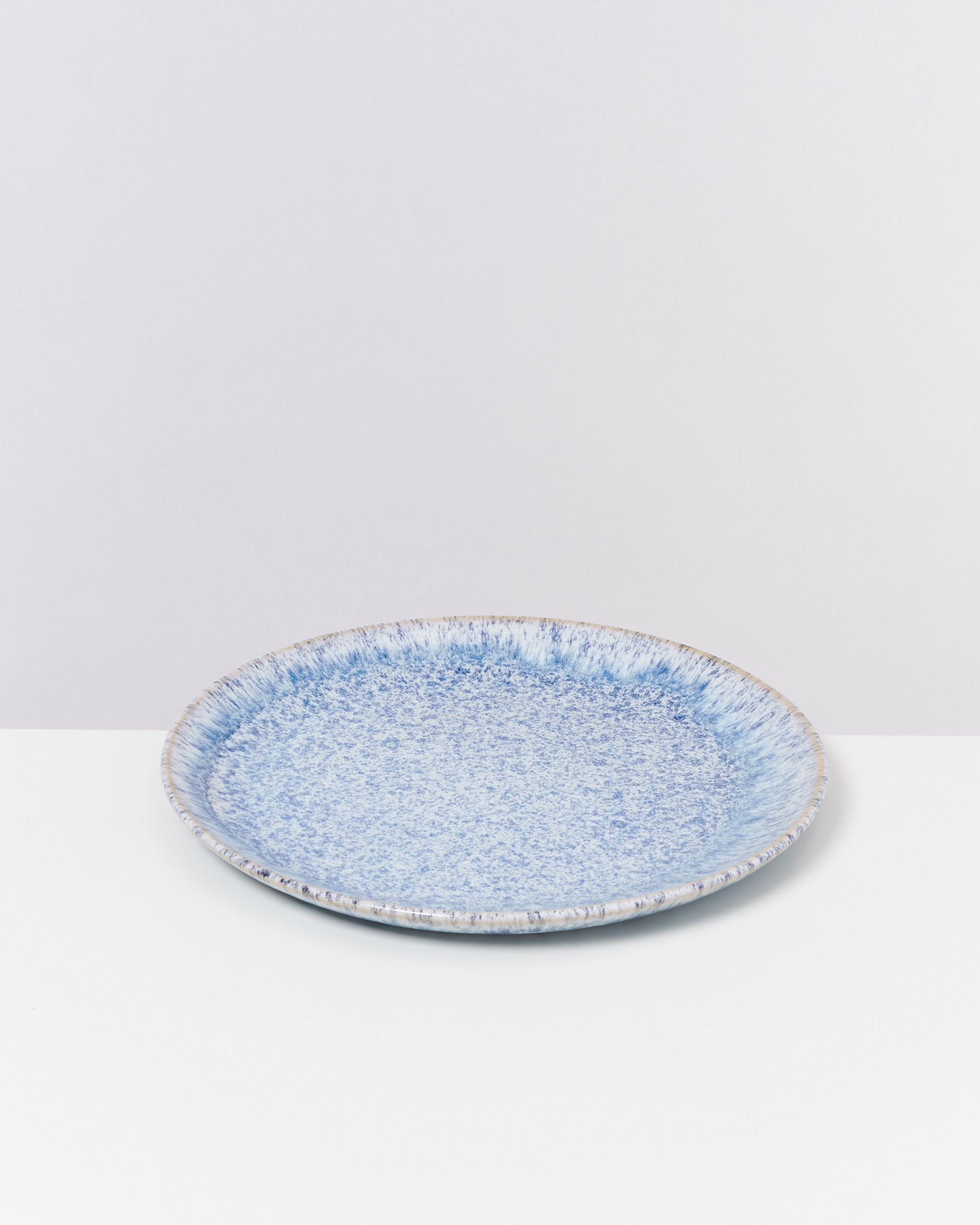 Keramikteller mit blauer, gesprenkelter Oberfläche auf weißem Hintergrund.
