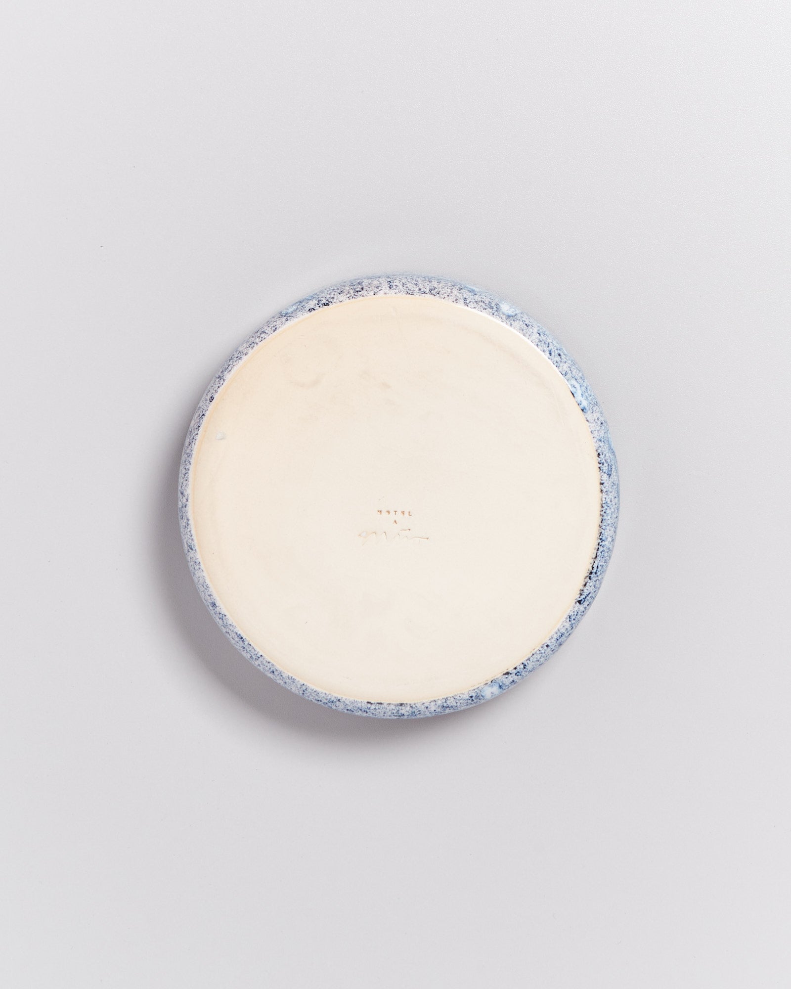 Runde, flache Keramikschale mit blauer und weißer Marmorierung, von oben betrachtet.