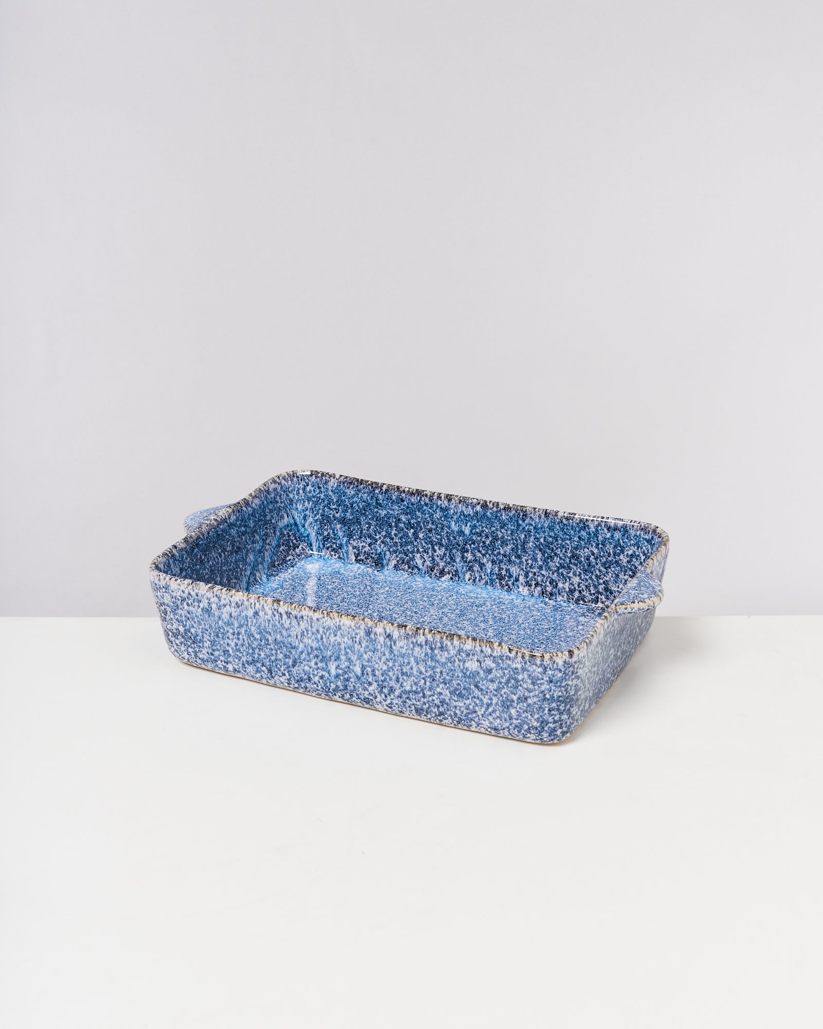 Blaue rechteckige Auflaufform mit gesprenkeltem Muster auf einem weißen Hintergrund.