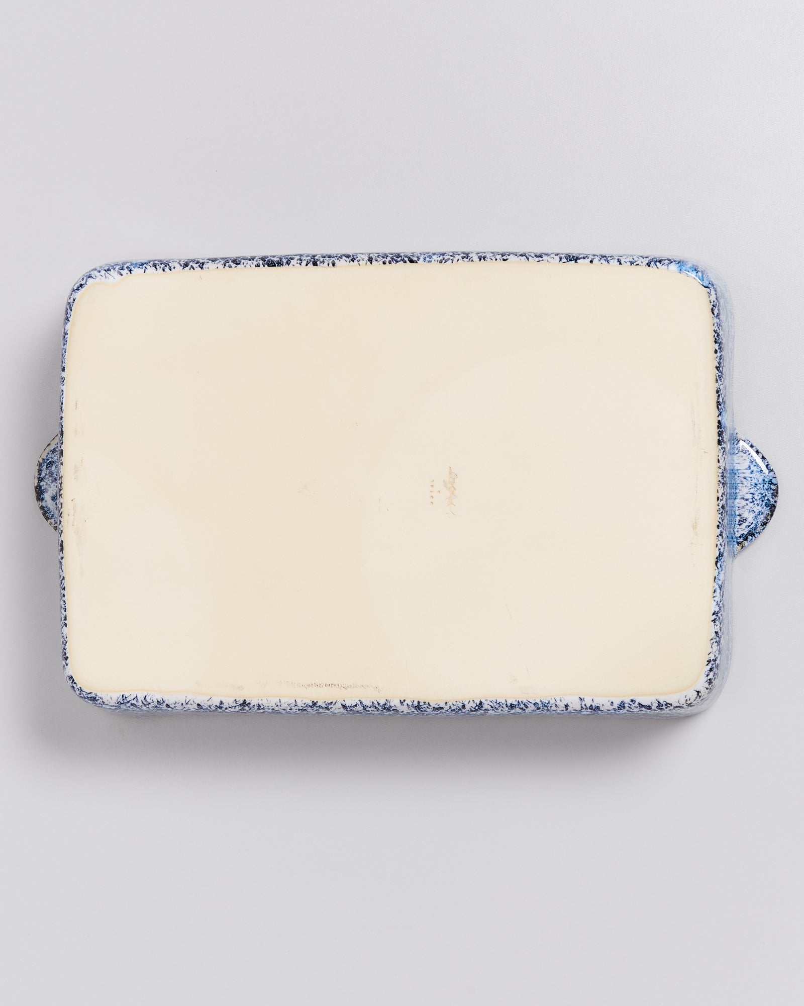 Rechteckige, cremefarbene Keramikplatte mit blauem Rand auf weißem Hintergrund.