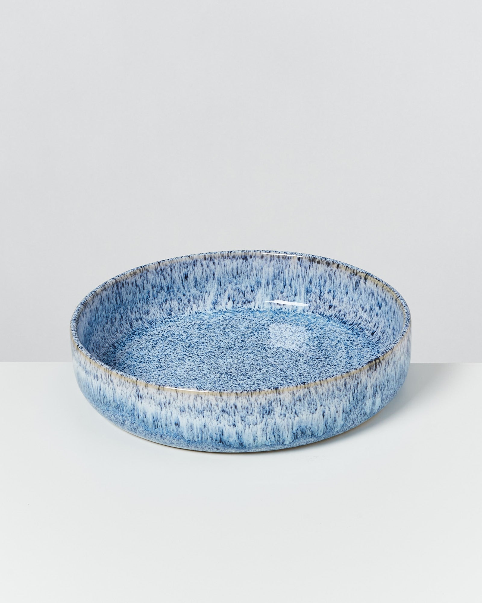 Blaue, runde Keramikschale mit gesprenkelter Oberfläche auf weißem Hintergrund.