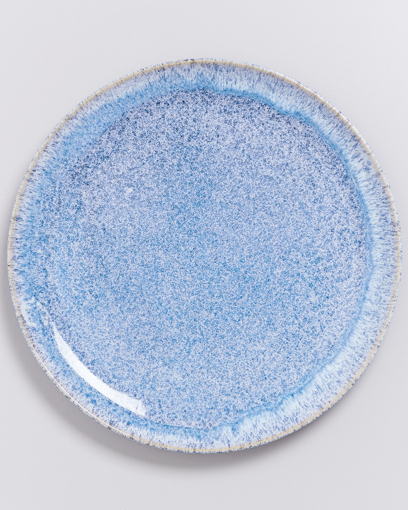 Blaue, gesprenkelte Keramikplatte auf weißem Hintergrund.