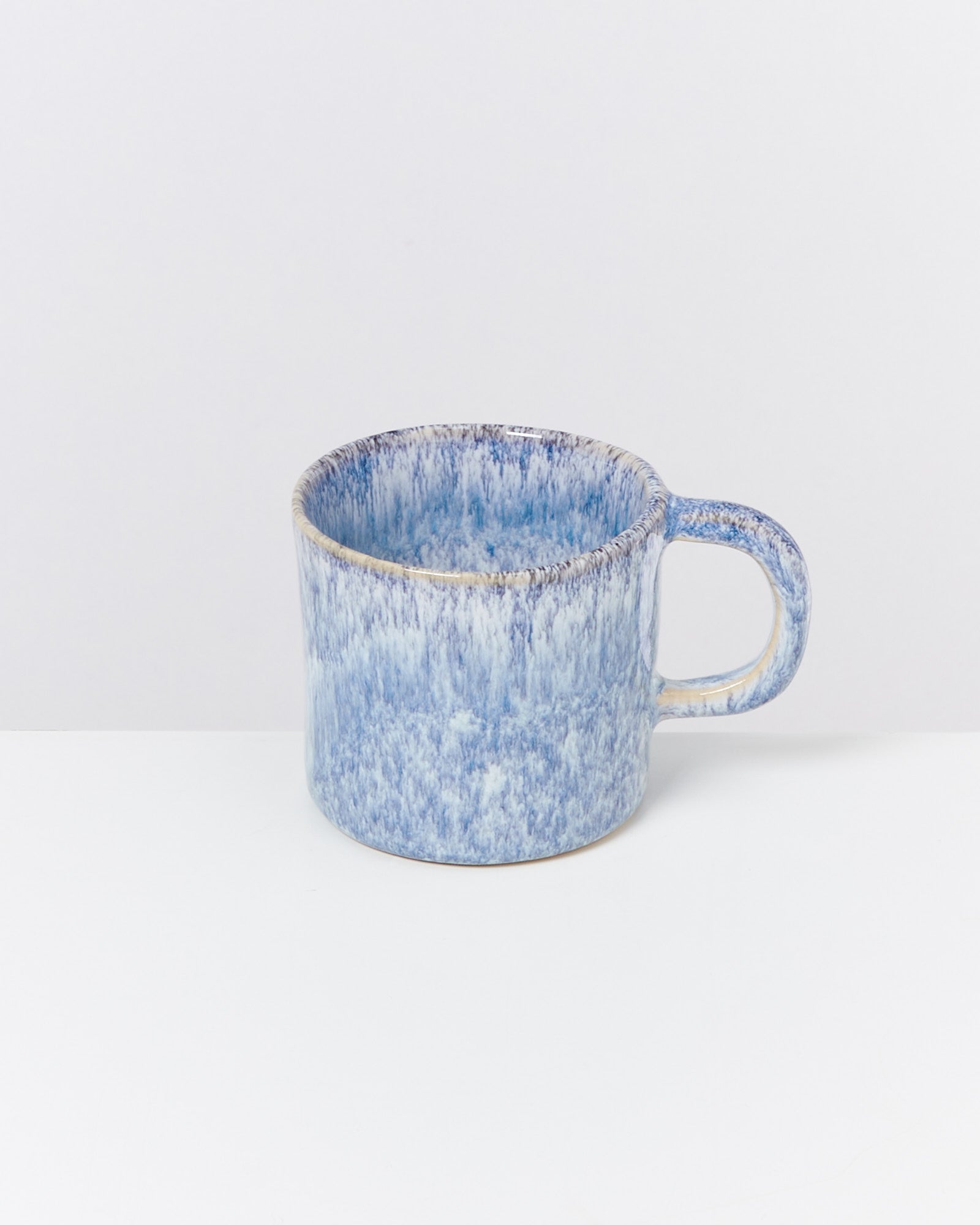 Blaue, gemusterte Keramiktasse mit Henkel auf weißem Hintergrund.