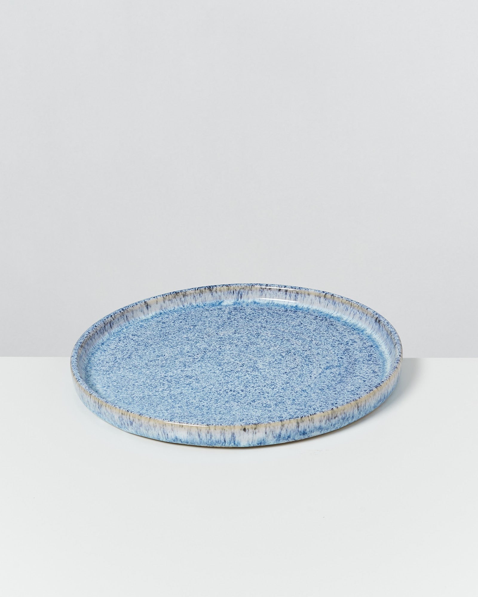 Ein blauer, gesprenkelter Keramikteller liegt auf einer weißen Oberfläche.