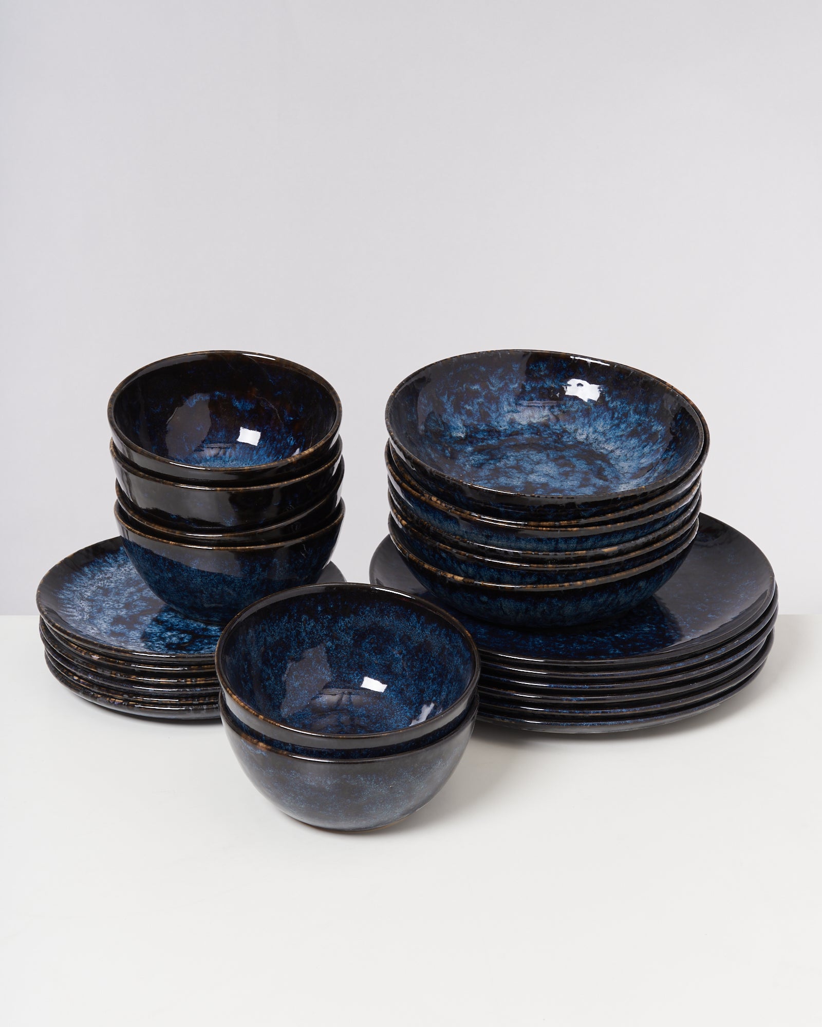 Mehrere gestapelte blaue Keramikschalen und Teller auf einer weißen Oberfläche.