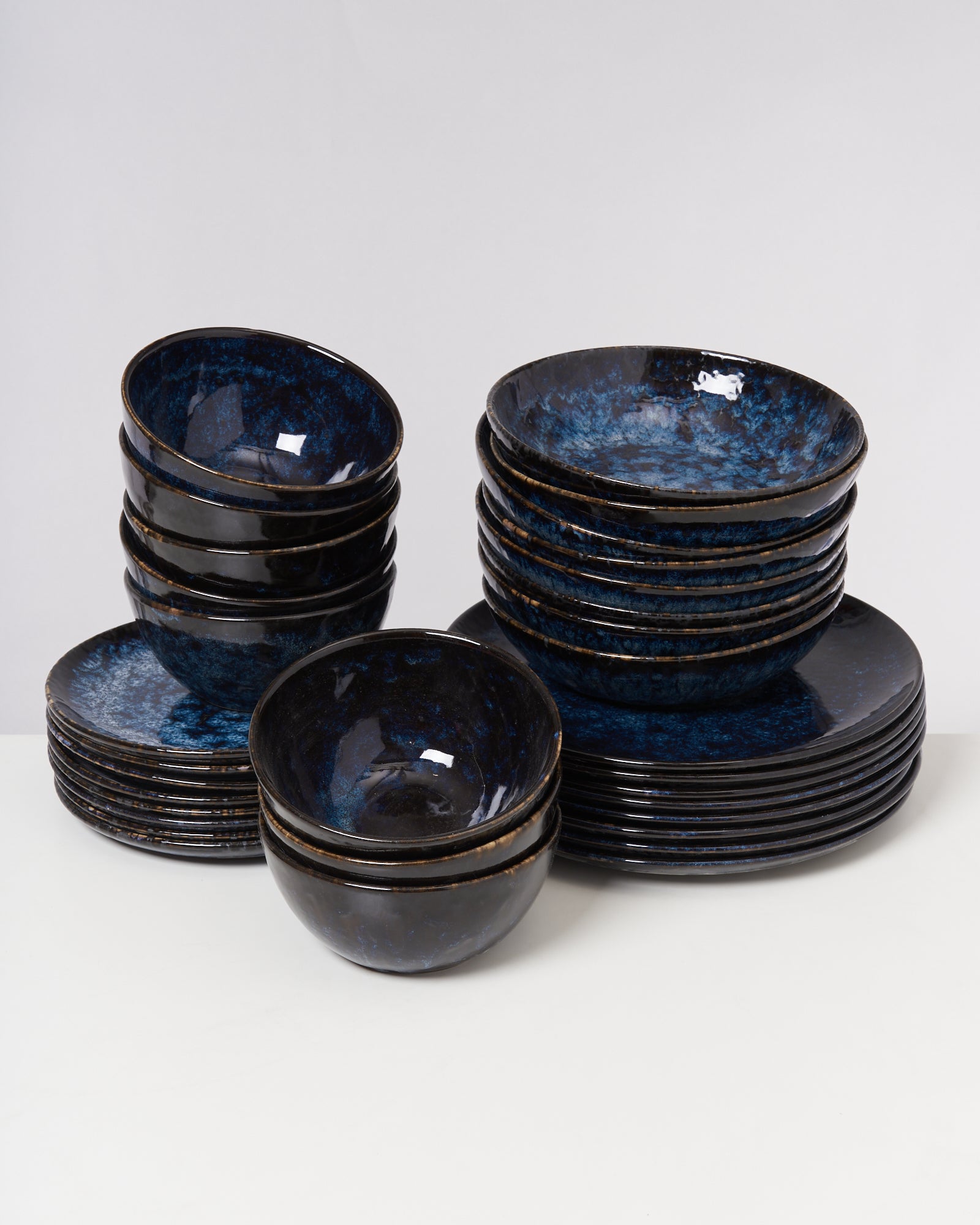 Stapel von blauen, glasierten Schüsseln und Tellern auf einem weißen Hintergrund.