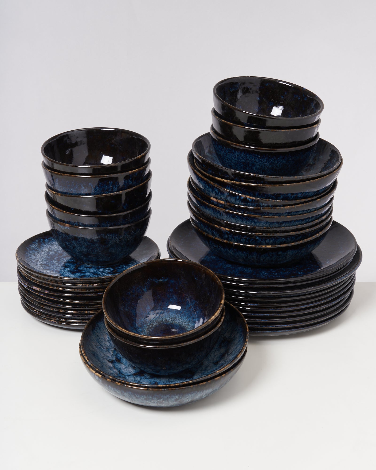 Stapel aus blauen Keramikschalen und -tellern auf einem weißen Hintergrund.