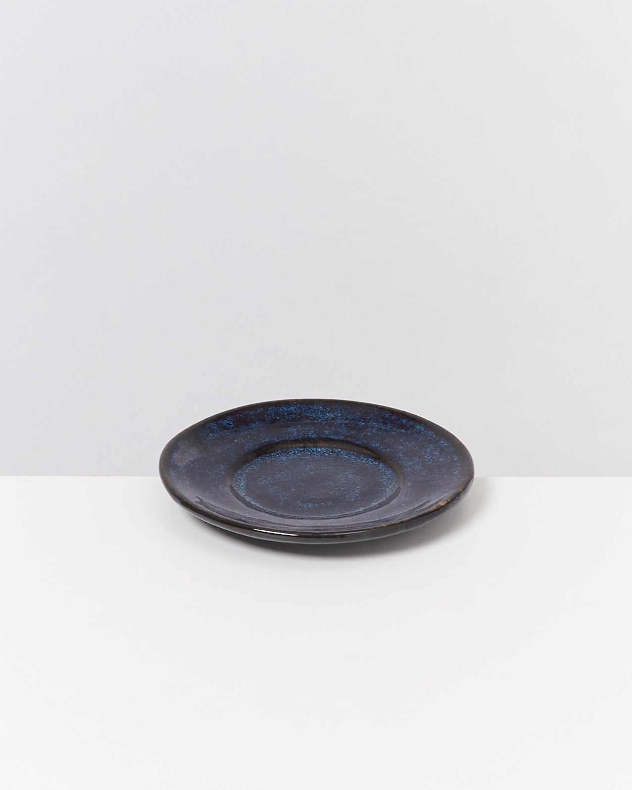 Blauer Keramikteller auf einem weißen Hintergrund.