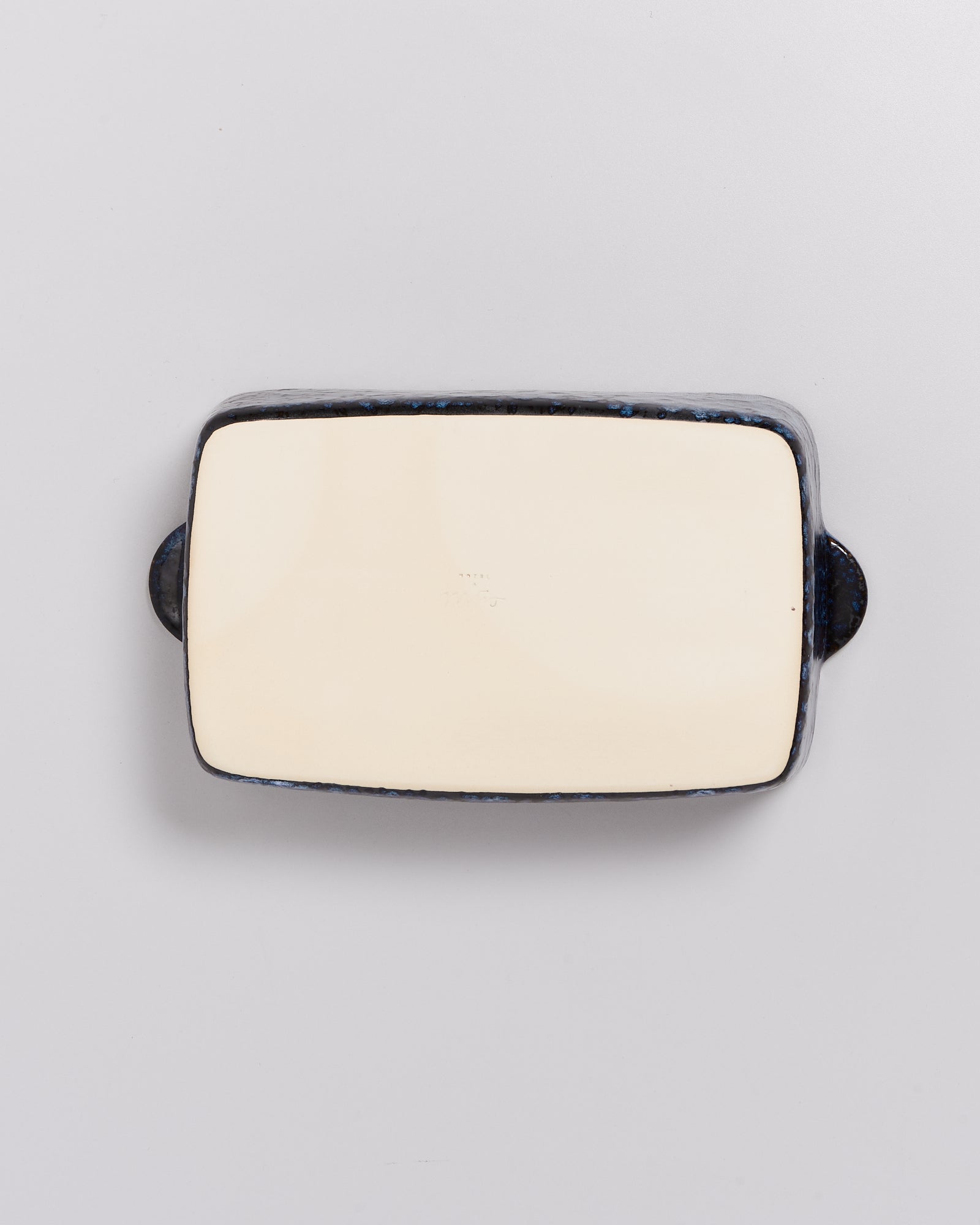 Rechteckiger, flacher Keramikteller mit dunklem Rand und hellbeiger Oberfläche auf weißem Hintergrund.
