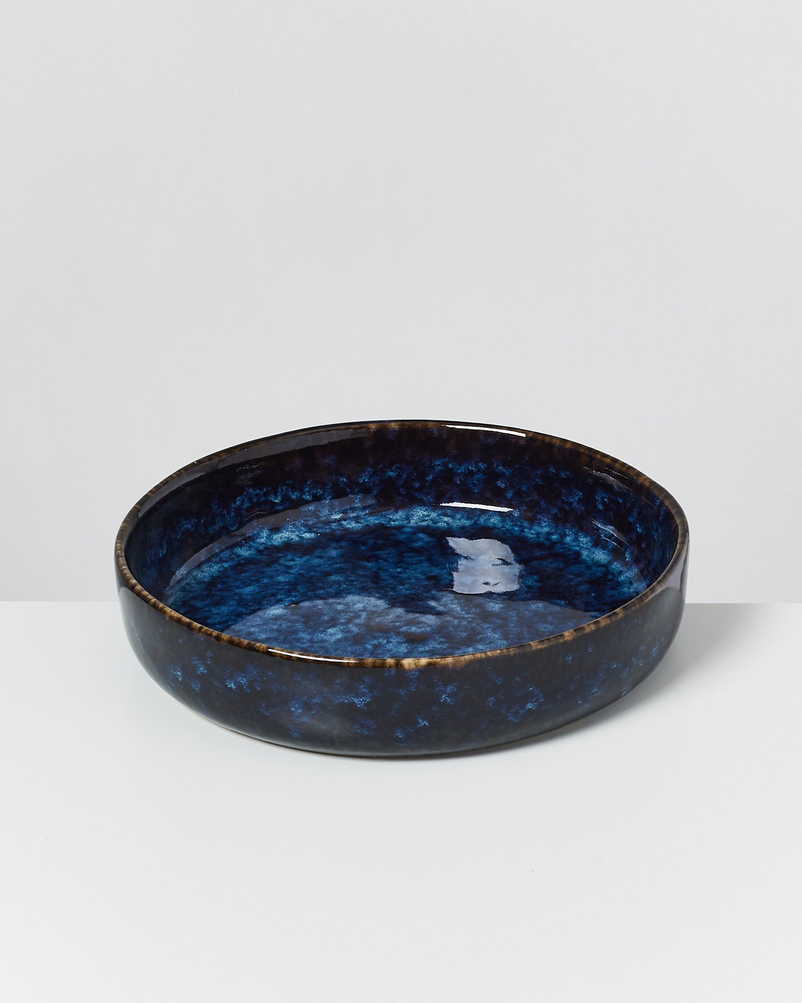 Dunkelblaue, runde Keramikschale mit glasiertem Finish auf weißem Hintergrund.